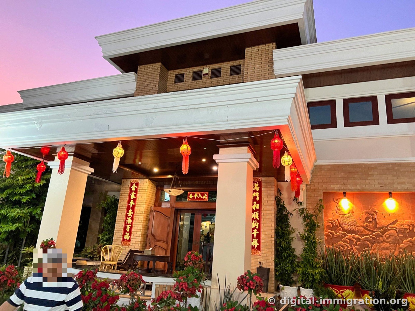 The main building entrance with red lanterns and Chinese couplets hanging, and a relief carving of a carp and waves illuminated on the right wall
