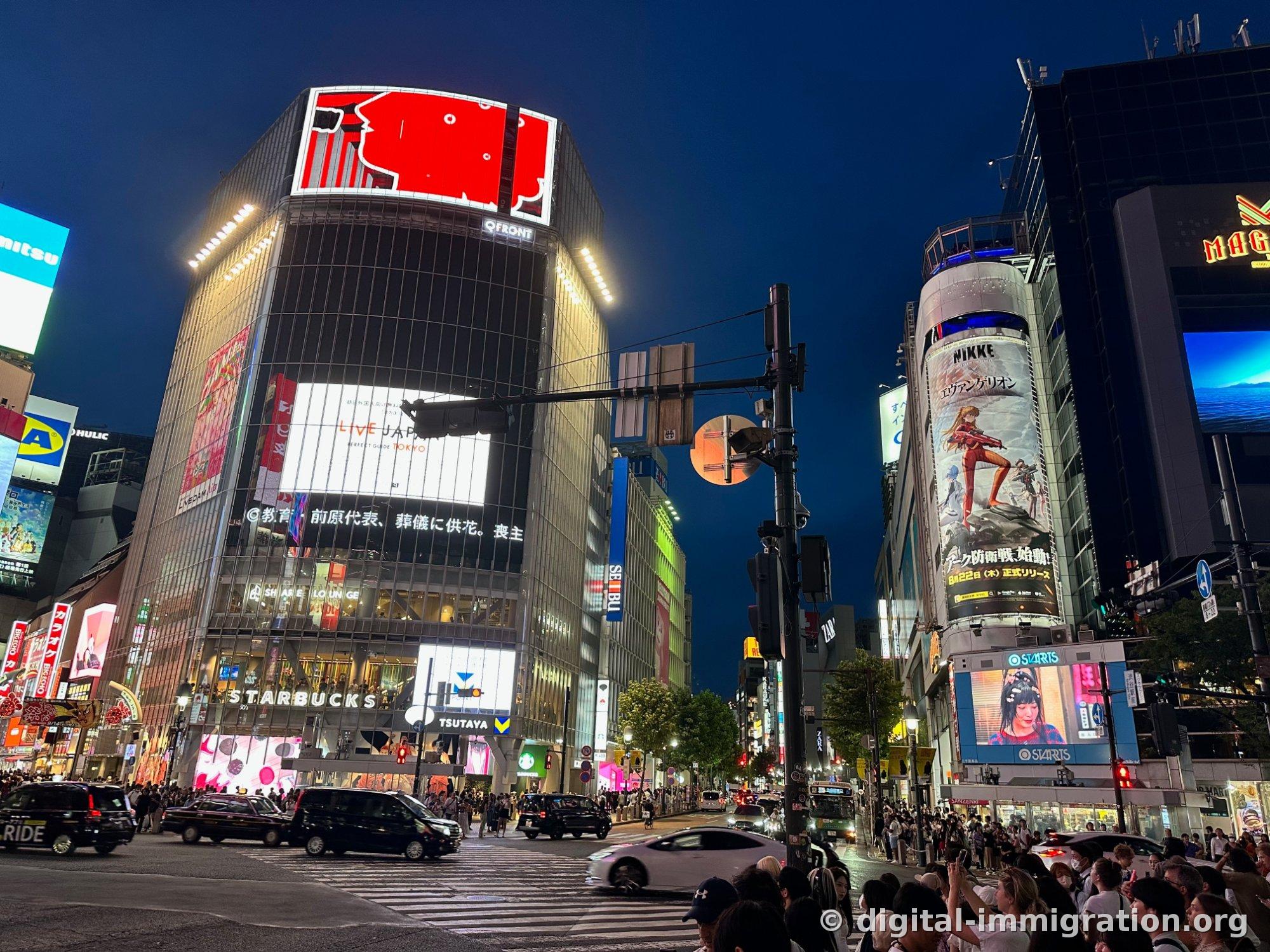 夜の渋谷スクランブル交差点、QFRONT建物の上部の赤い大型スクリーンとスターバックス、ツタヤの看板が点灯している