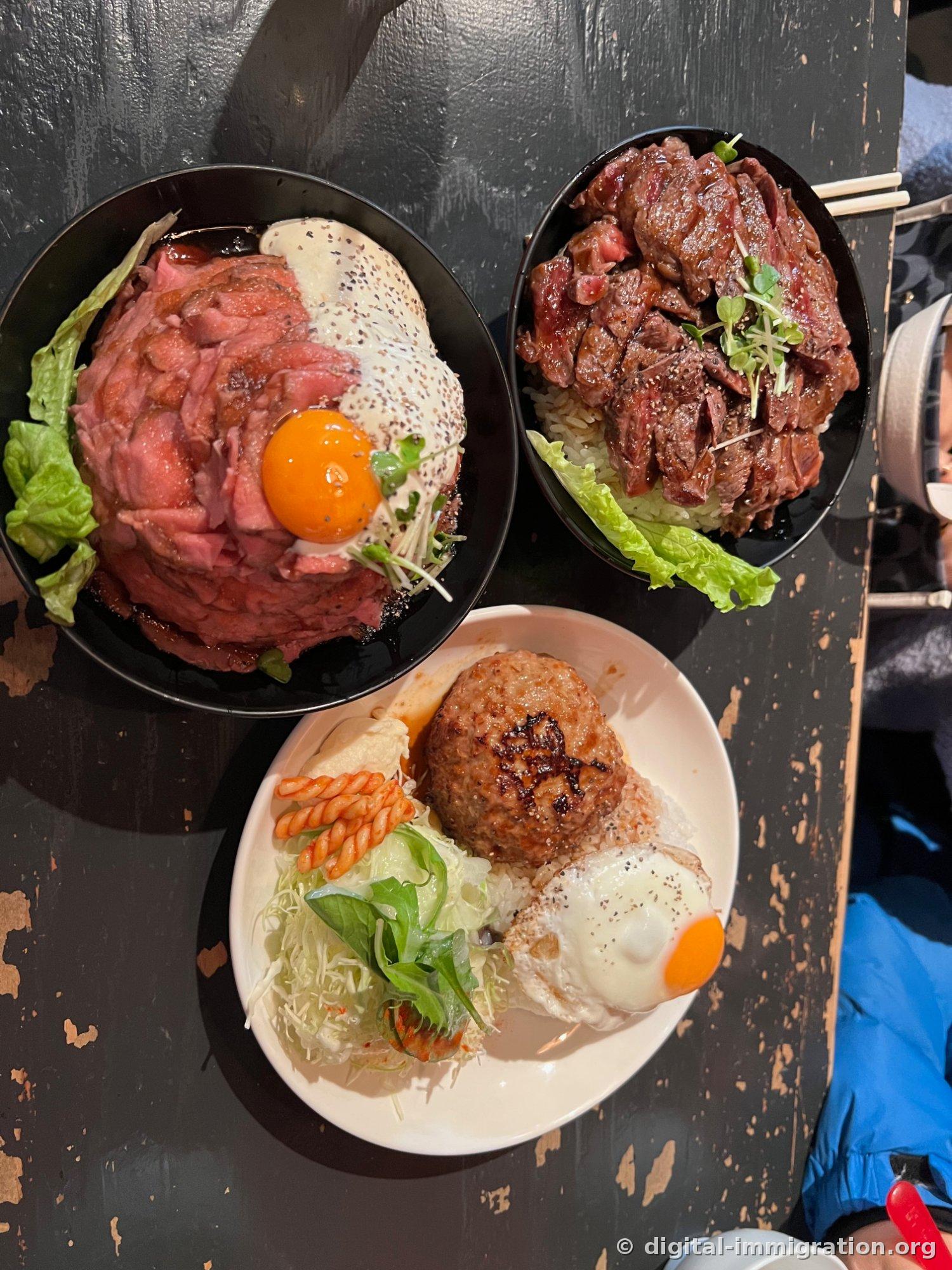 Trois assiettes placées ensemble sur une table en bois dont la peinture s'écaille : roast beef donburi, steak donburi et set de steak haché