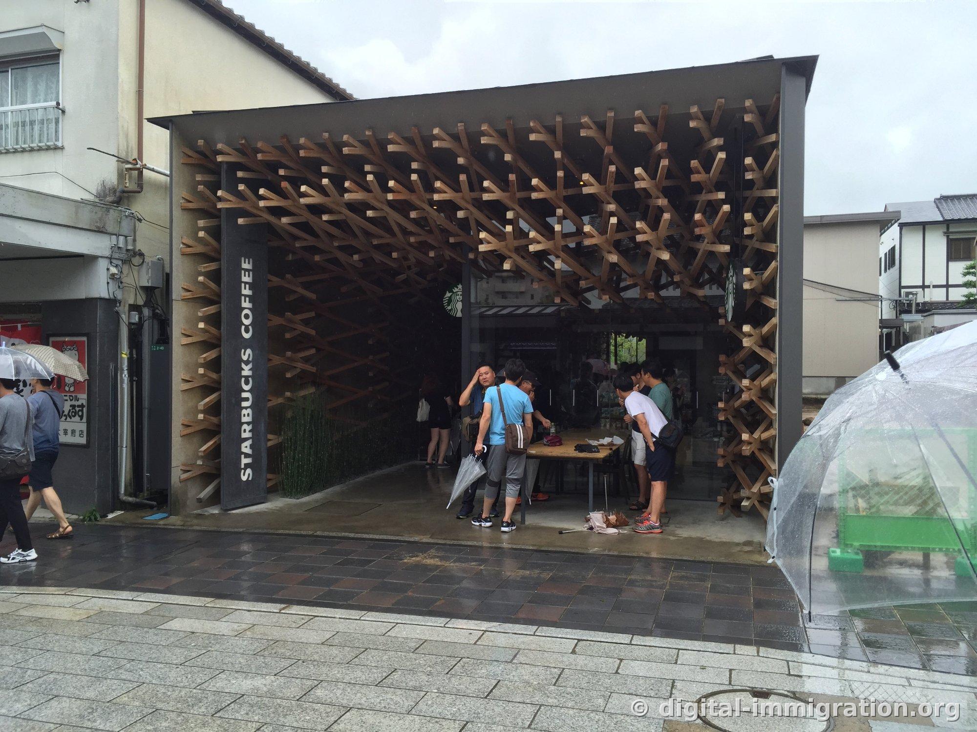 Exterior of Dazaifu Starbucks with 'STARBUCKS COFFEE' vertical sign and diagonal wooden lattice facade