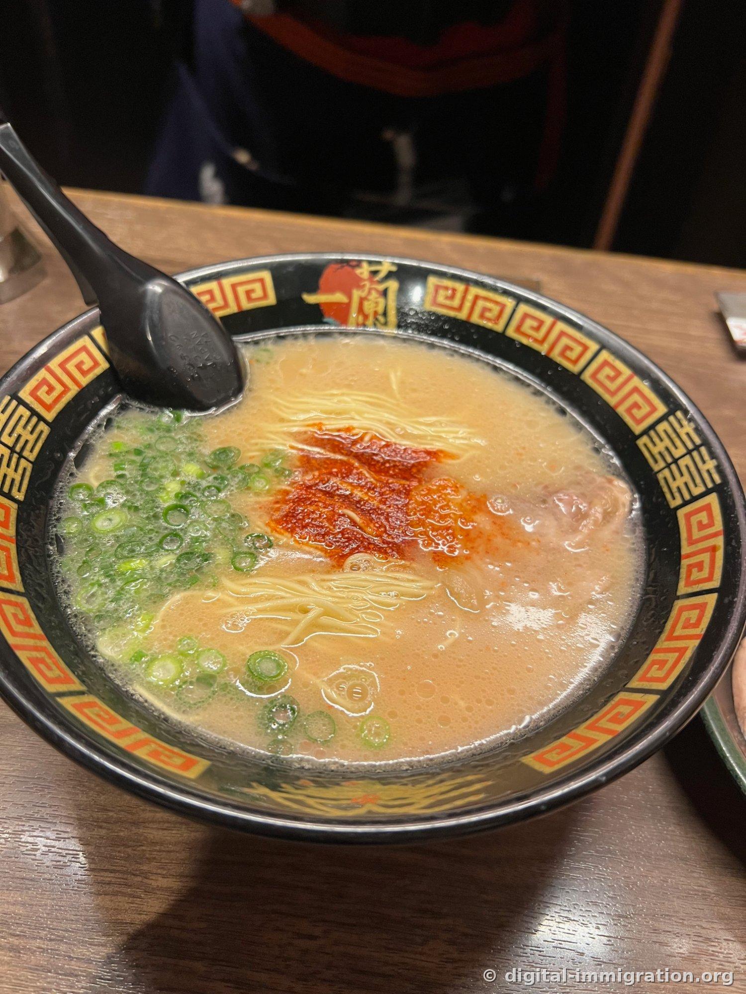 Ichiran-patterned bowl with creamy tonkotsu ramen, red secret sauce in the center and generously piled green scallions on the left, thin noodles and one slice of char siu