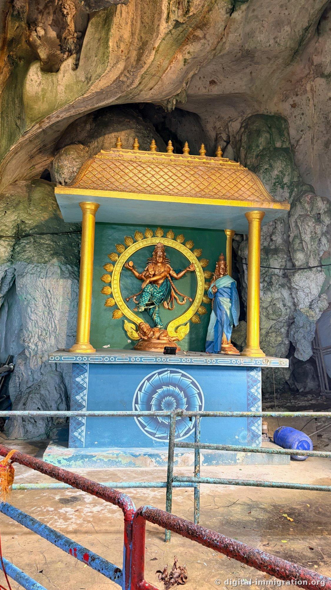 洞窟の壁の下の金色の柱と屋根を付けた祠、炎の輪の中で踊るナタラジャ像と青い衣装の女神像が祀られている