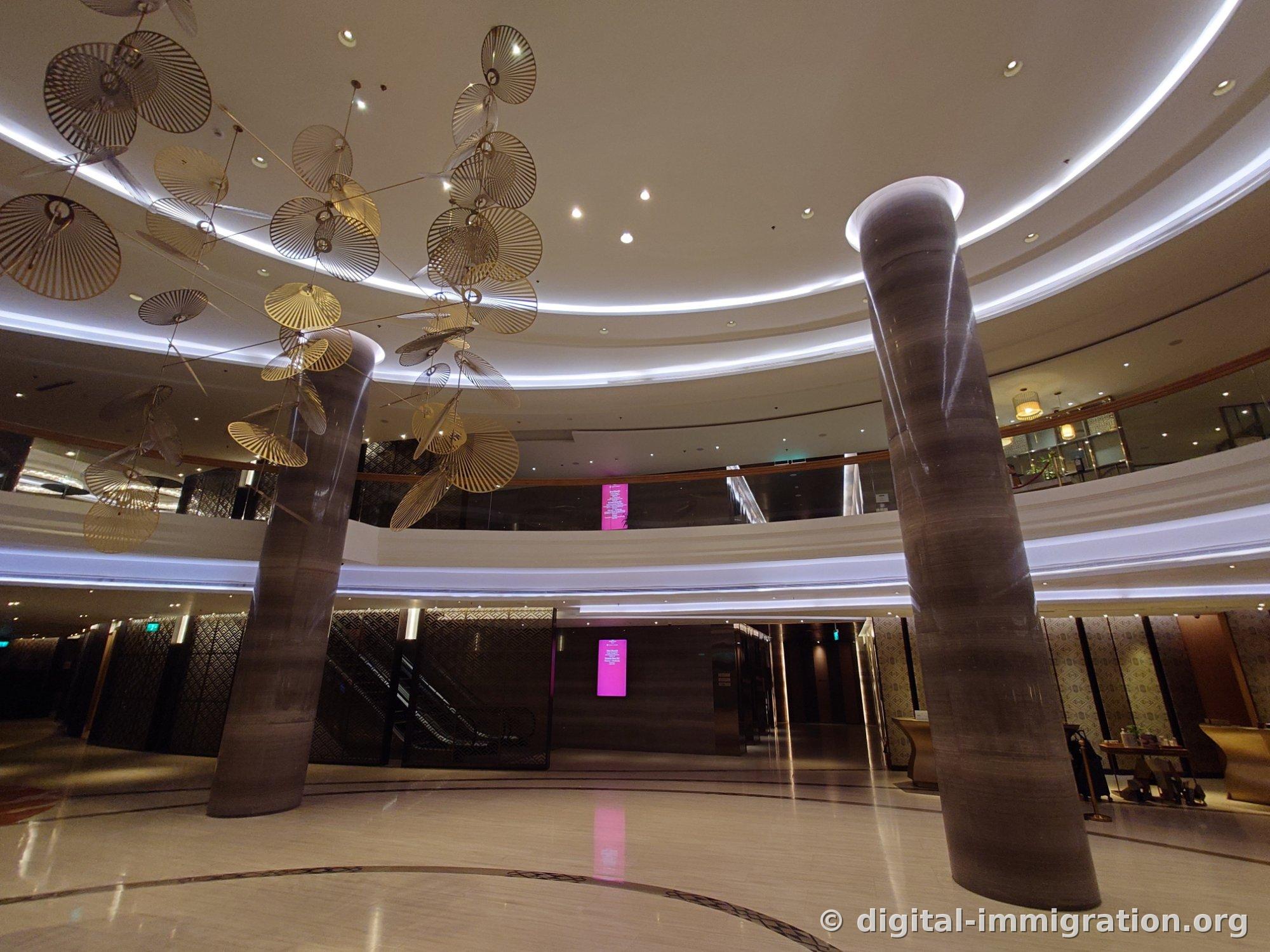 Crowne Plaza Vientiane lobby with gold umbrella-shaped objects hanging from the ceiling and two marble pillars