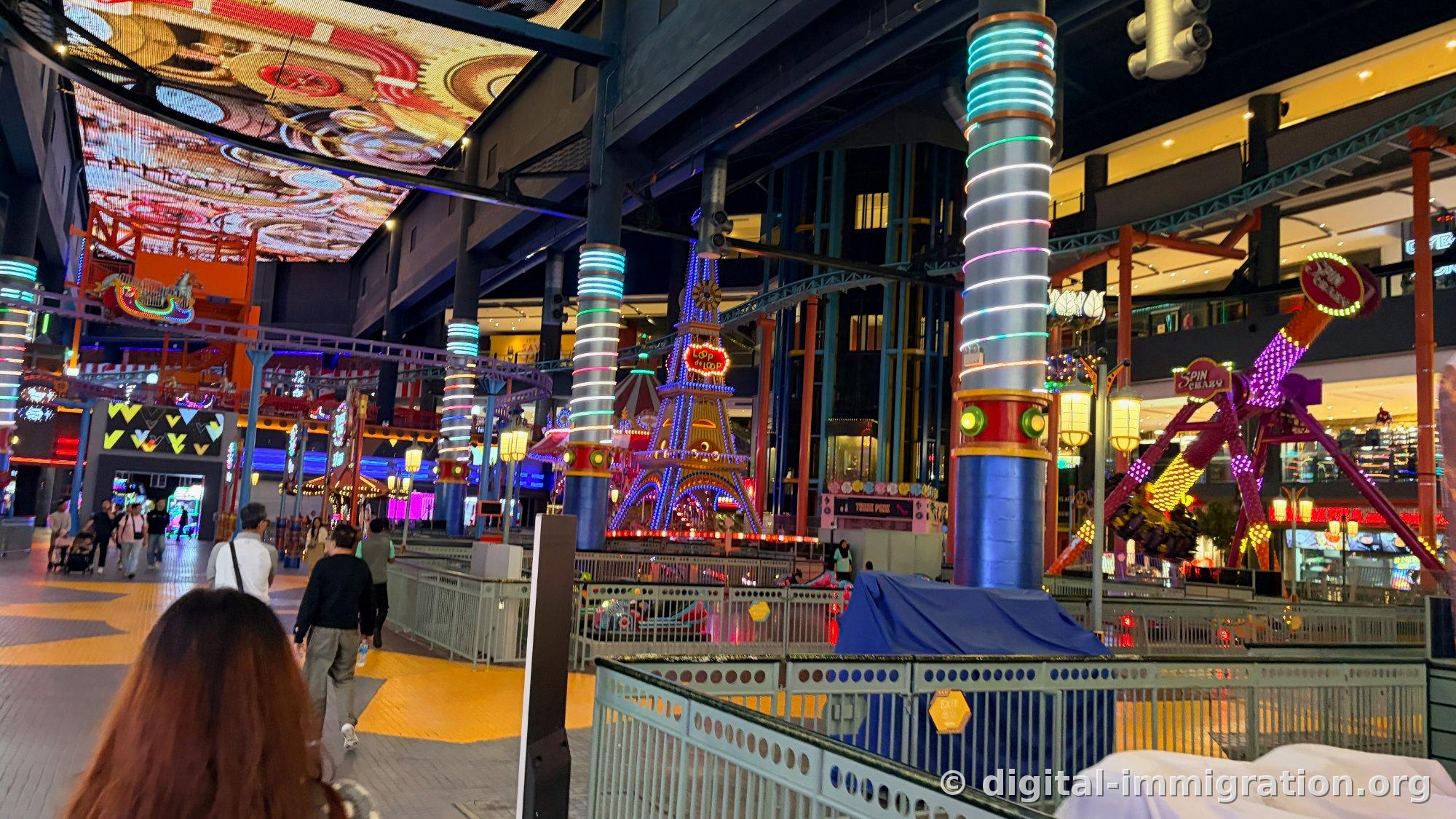 Indoor theme park blue light Eiffel Tower-shaped Loop de Loop structure and purple Spin Crazy ride with ceiling LED screen