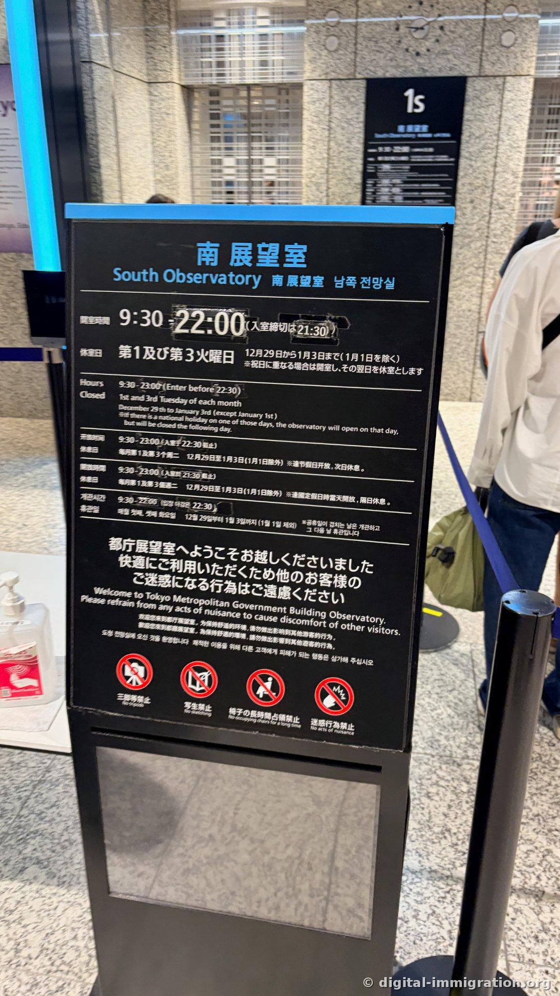 Panneau noir indiquant les horaires d'ouverture et les jours de fermeture de la salle d'observation sud en japonais, anglais, chinois et coréen, avec l'indication du 1er étage en haut à droite
