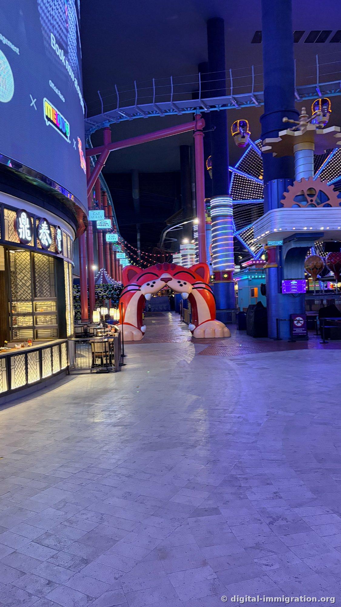 Round mall atrium with white spheres hanging from ceiling, golden horse sculpture with flame decorations in center, large performance screen, SkyCasino entrance at back