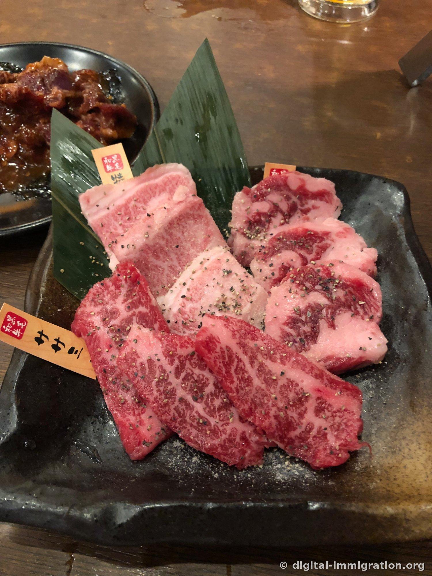 Viande Wagyu crue saupoudrée de poivre dans une assiette carrée noire avec une étiquette Wagyu plantée