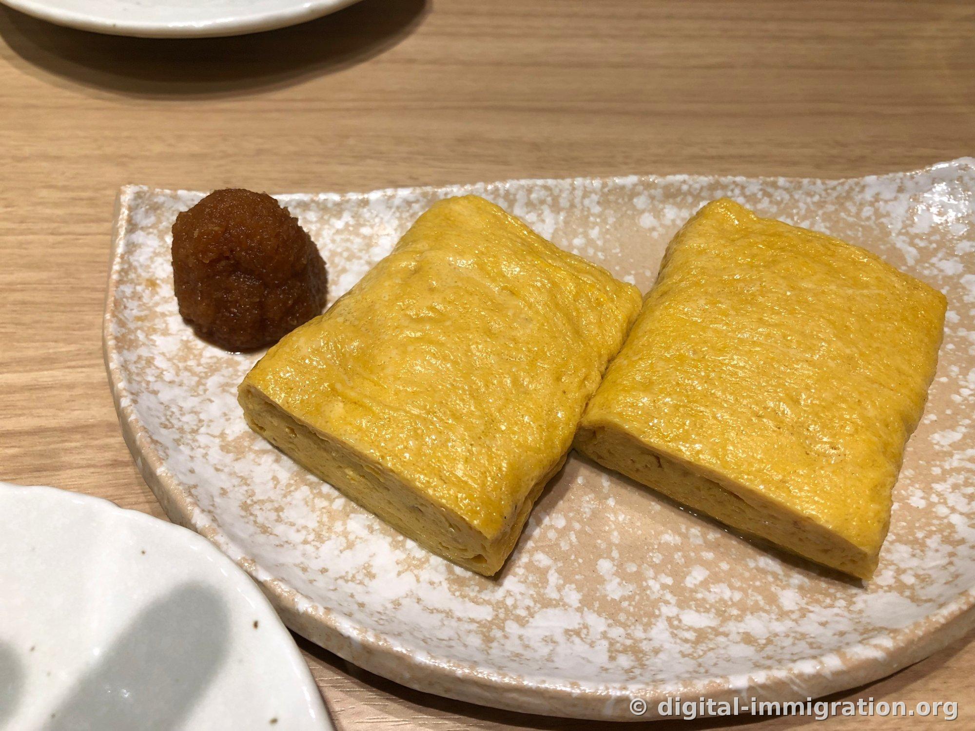 Two tamagoyaki pieces and a mound of grated radish arranged on a plate
