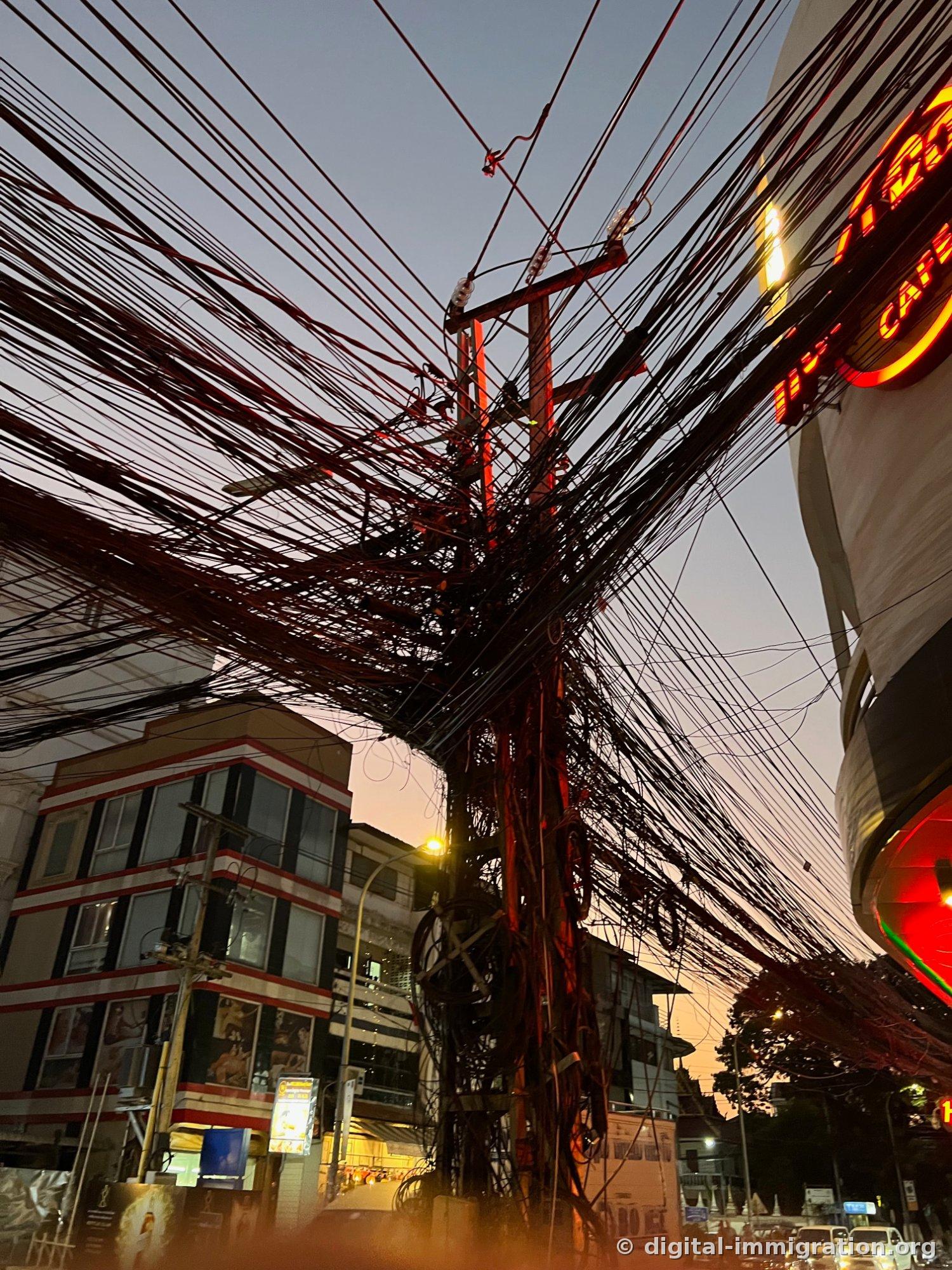 해질녘 보랏빛 하늘 아래 수십 가닥의 전선이 얽힌 전봇대와 오른쪽에 붉게 켜진 Hard Rock Cafe 네온 간판