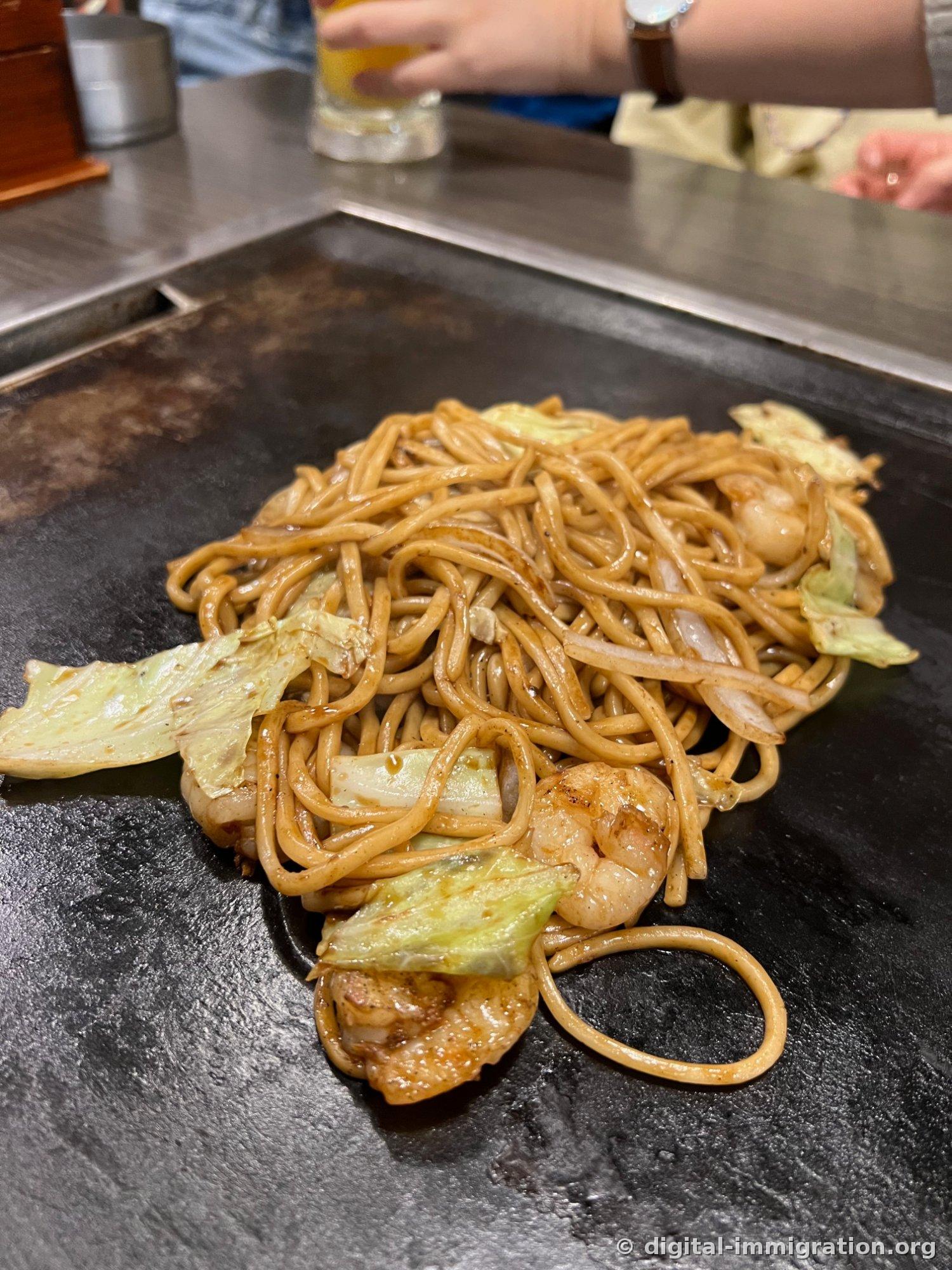 Yakisoba aux nouilles épaisses cuites avec des crevettes et du chou sur la plaque de cuisson du restaurant