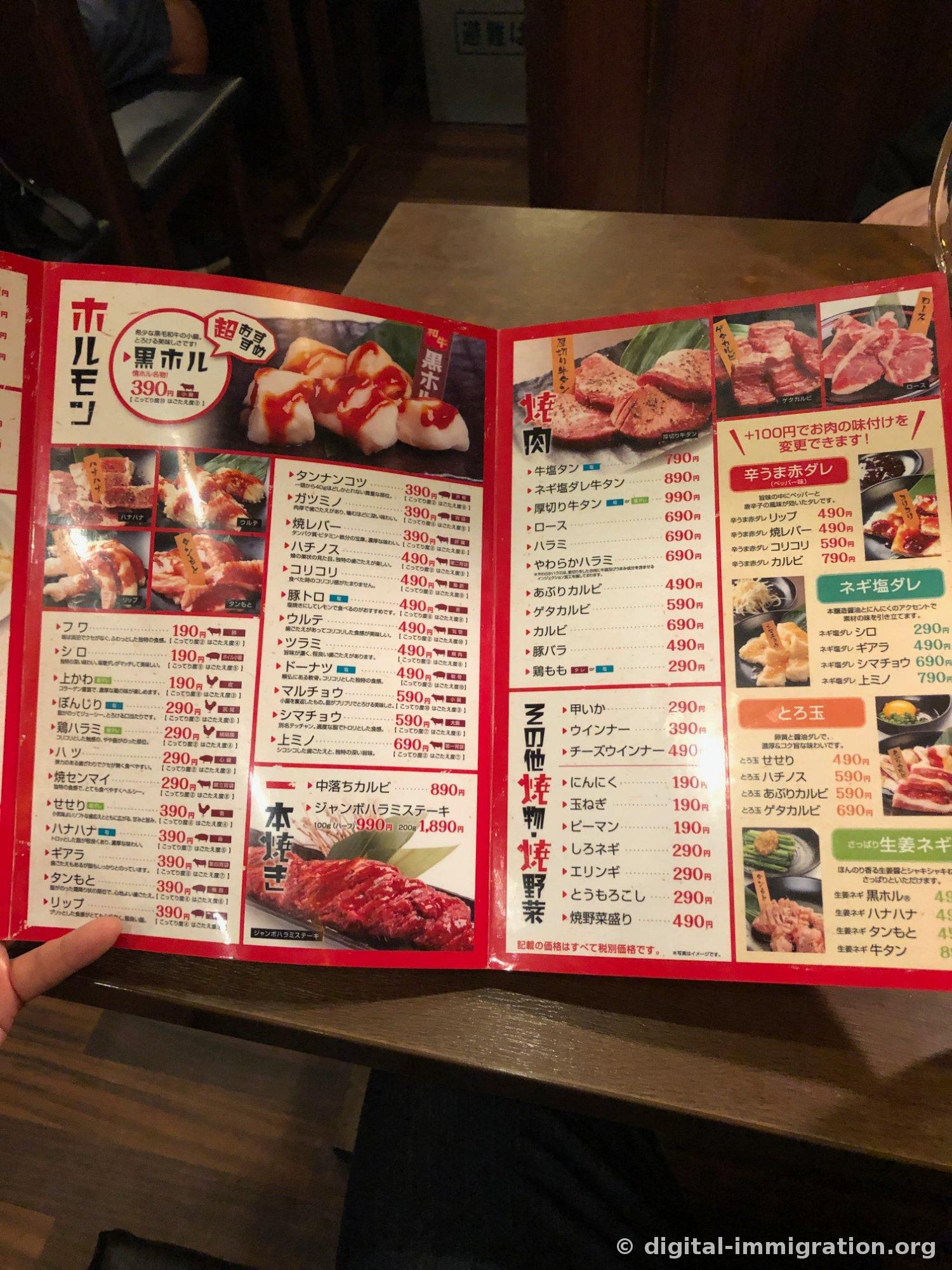 An open menu densely packed with horumon and yakiniku prices, showing Kurohor 390 yen on the left and gyutan, loin, harami with red sauce and garlic-salt marinade options on the right