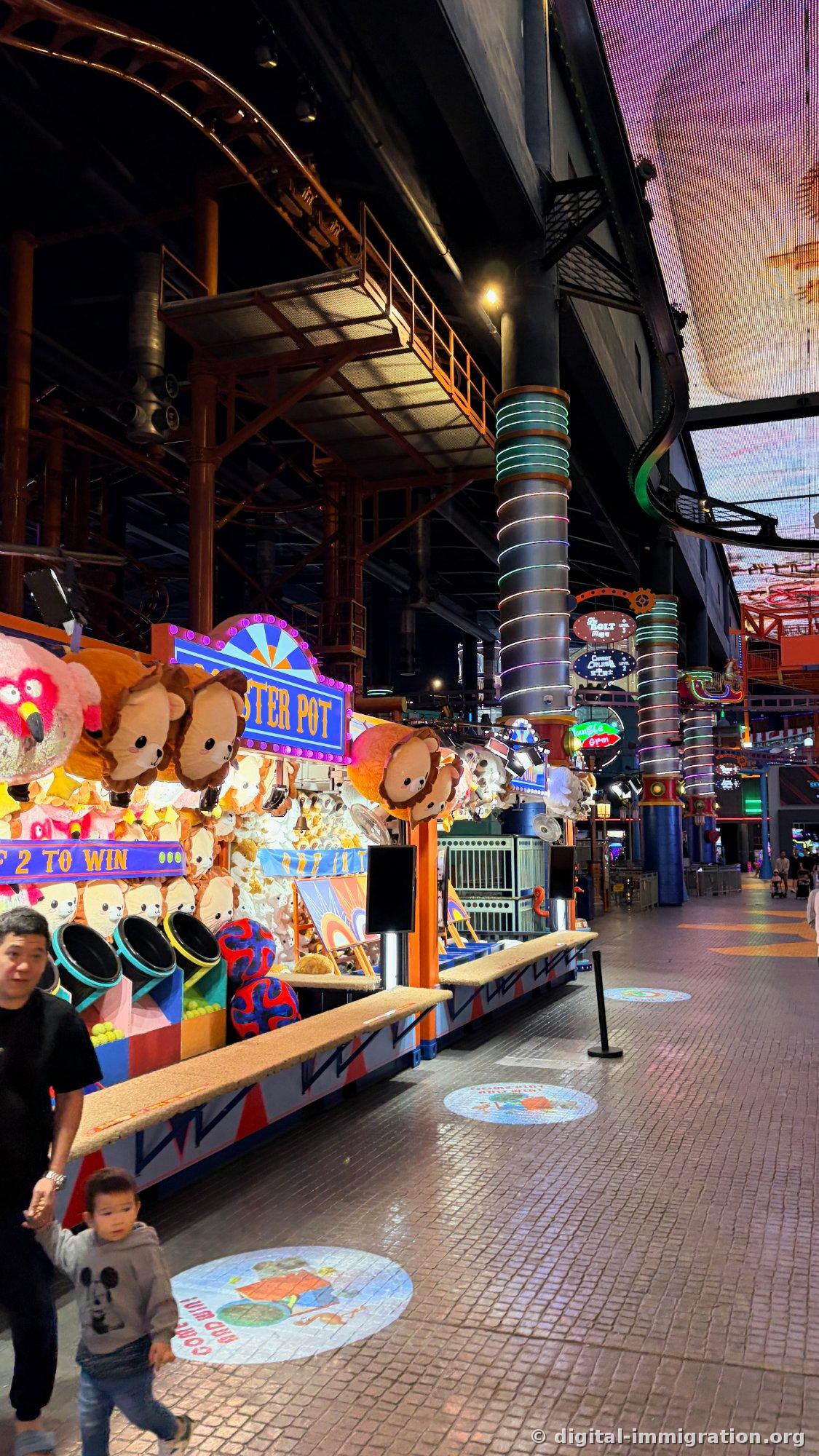 LOBSTER POT game booth filled with plush toys and child and adult passing by in indoor theme park corridor