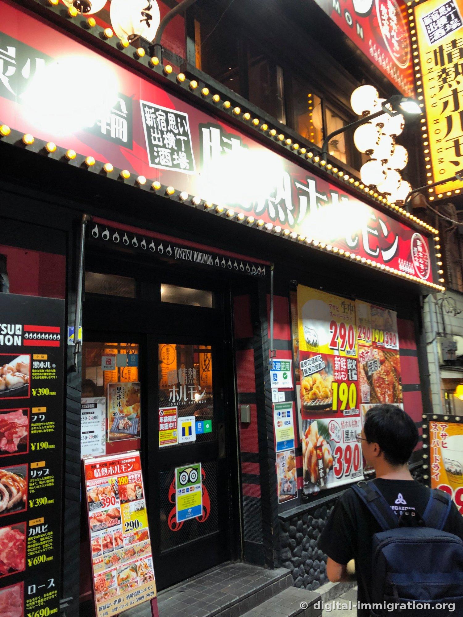 L'entrée de Jonetsu Hormon avec une enseigne rouge à ampoules et un panneau noir de menu à gauche