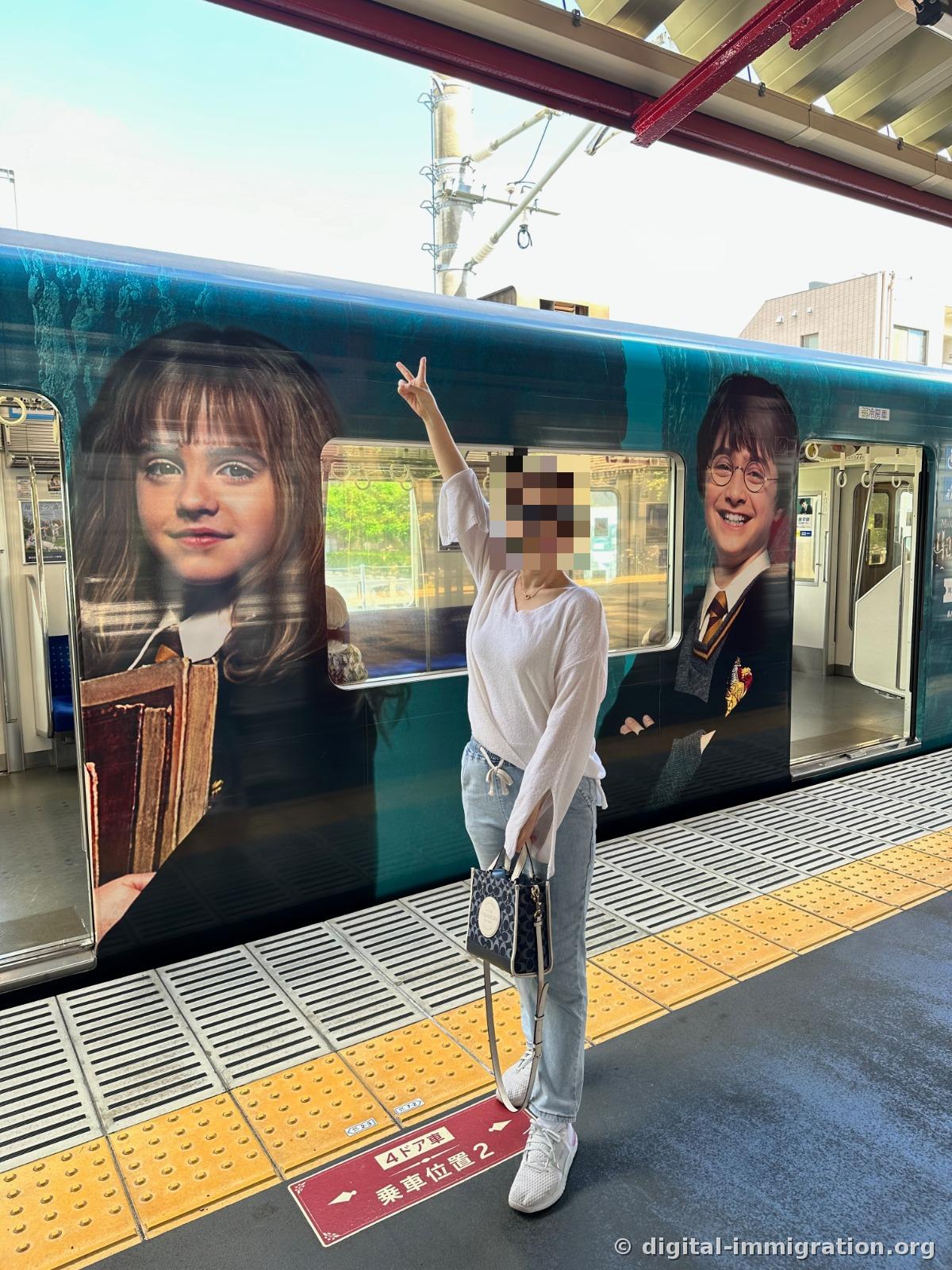 A person in a white knit sweater pointing upward in front of the same wrapped train