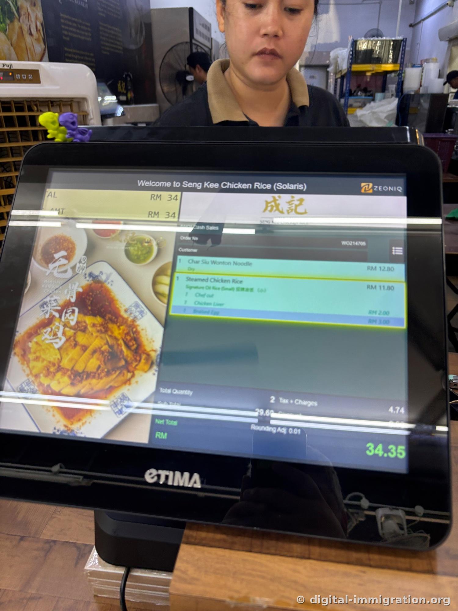 POS payment screen turned toward the customer. Order details show Char Siu Wonton Noodle RM12.80, Steamed Chicken Rice RM11.80, and total of 34.35
