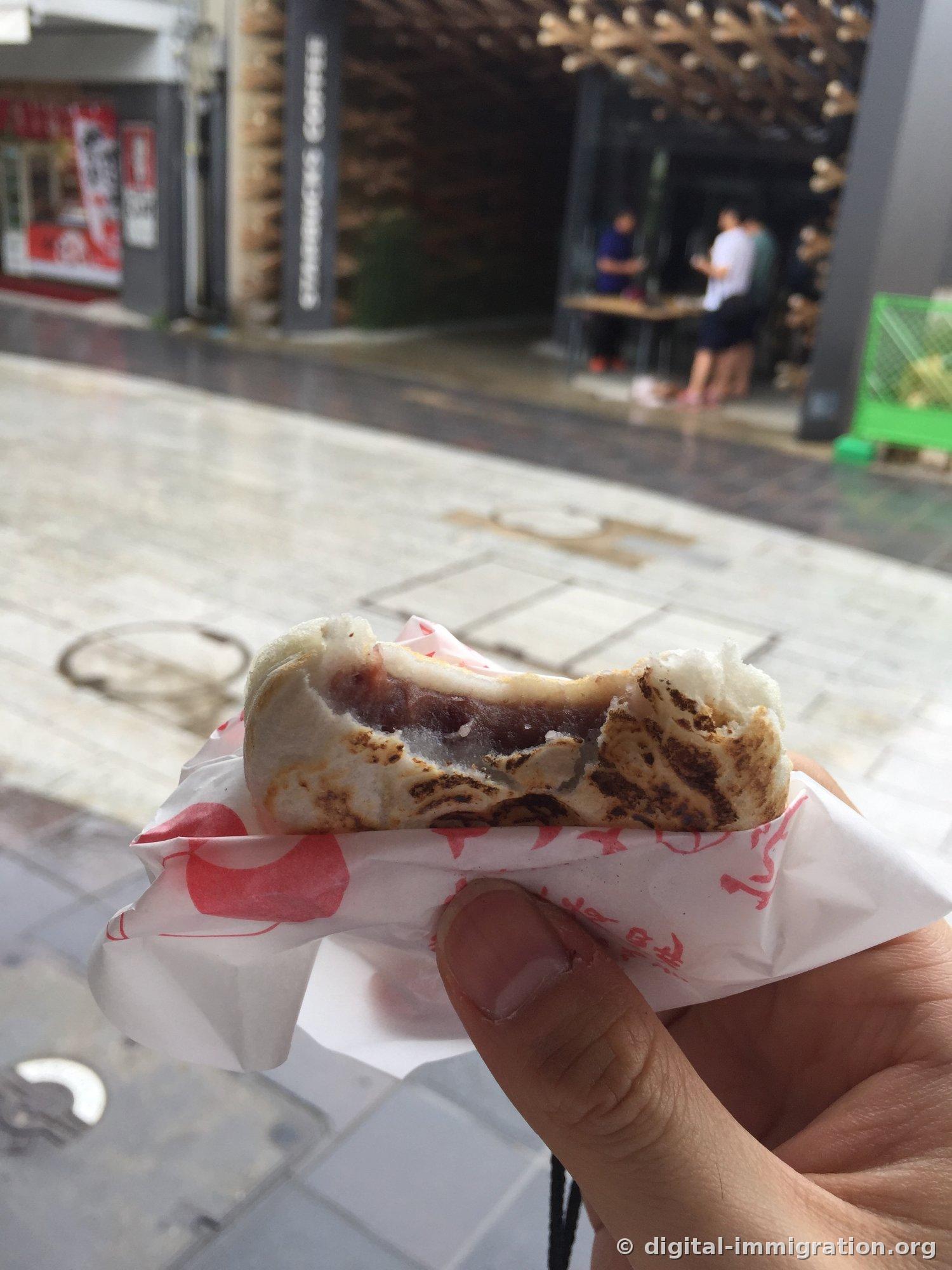 Cross-section of umegaemochi with a bite taken out, red bean filling exposed, char marks on the glutinous rice skin