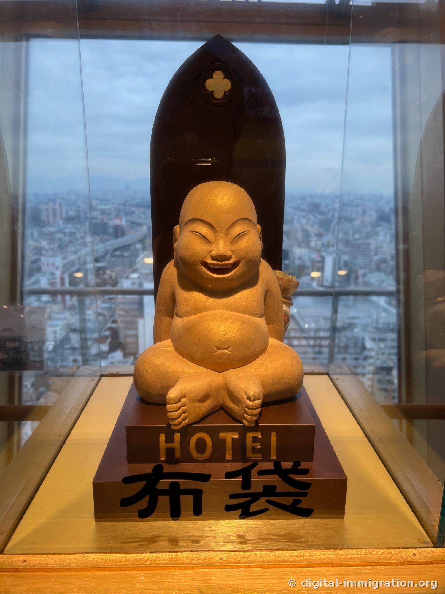 A wooden statue of Hotei revealing his belly and laughing broadly