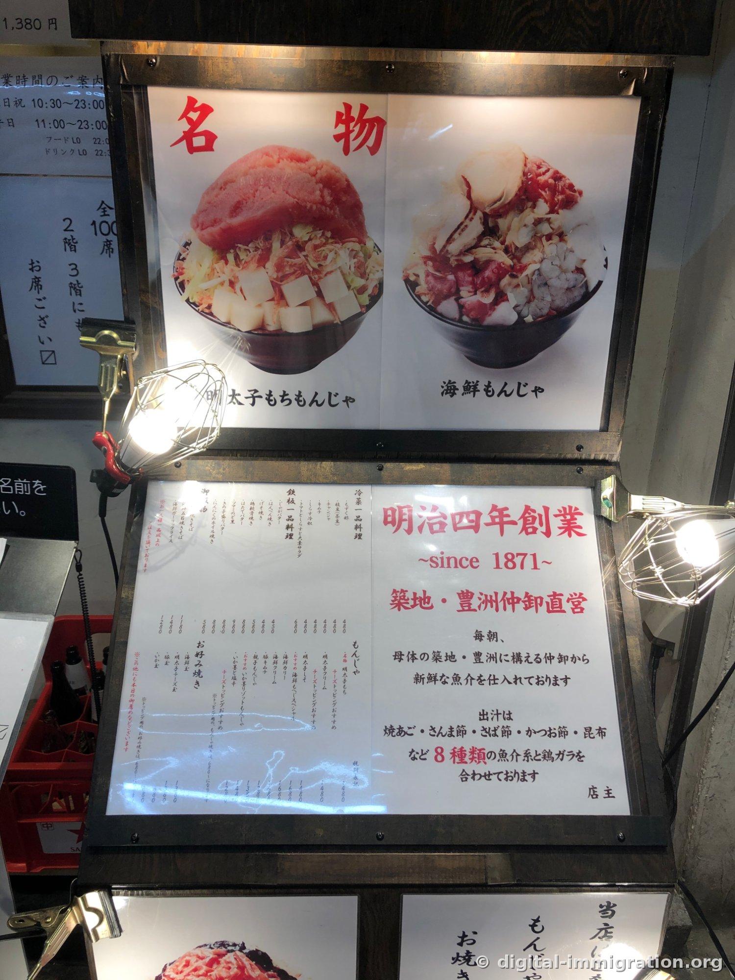 가게 앞 메뉴판. '명물' 명란모찌 몬자와 해산물 몬자 사진, 옆에 '明治四年創業 since 1871 築地·豊洲仲卸直営' 안내문
