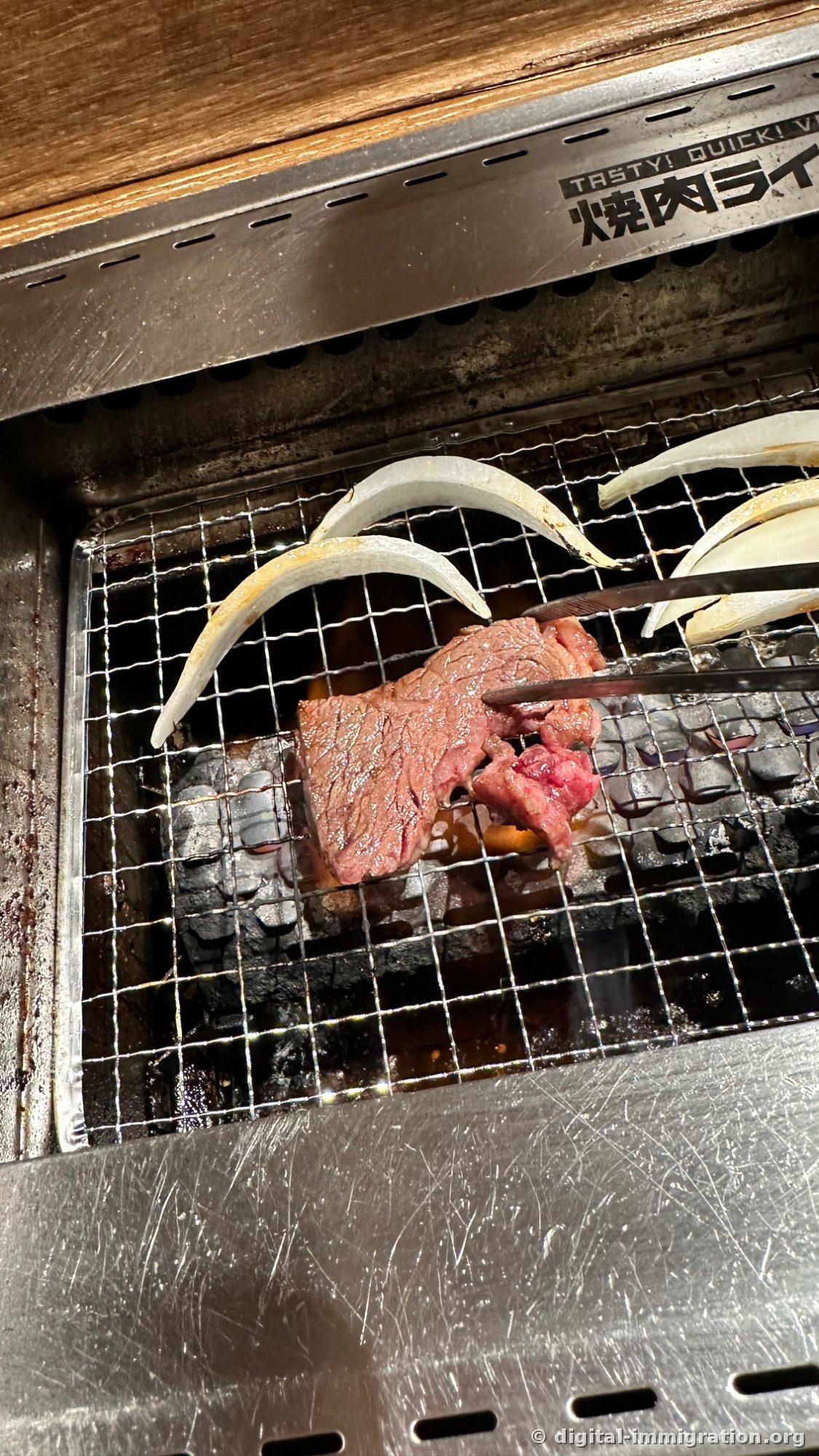Sur la grille du foyer, trois tranches d'oignon et un morceau de bavette rouge, placés à la pince