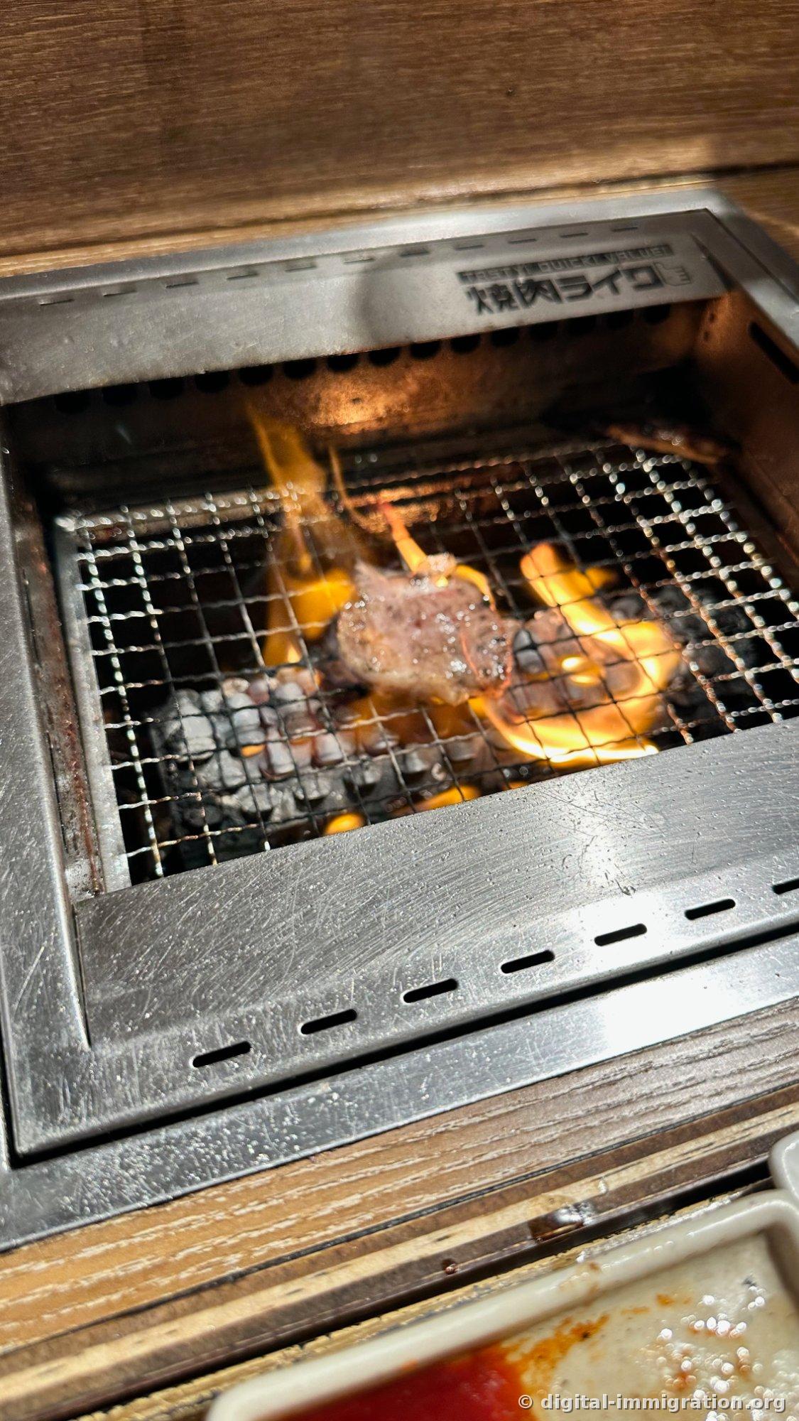 Gros plan d'un morceau de viande en train de cuire au cœur des flammes qui engloutissent la grille