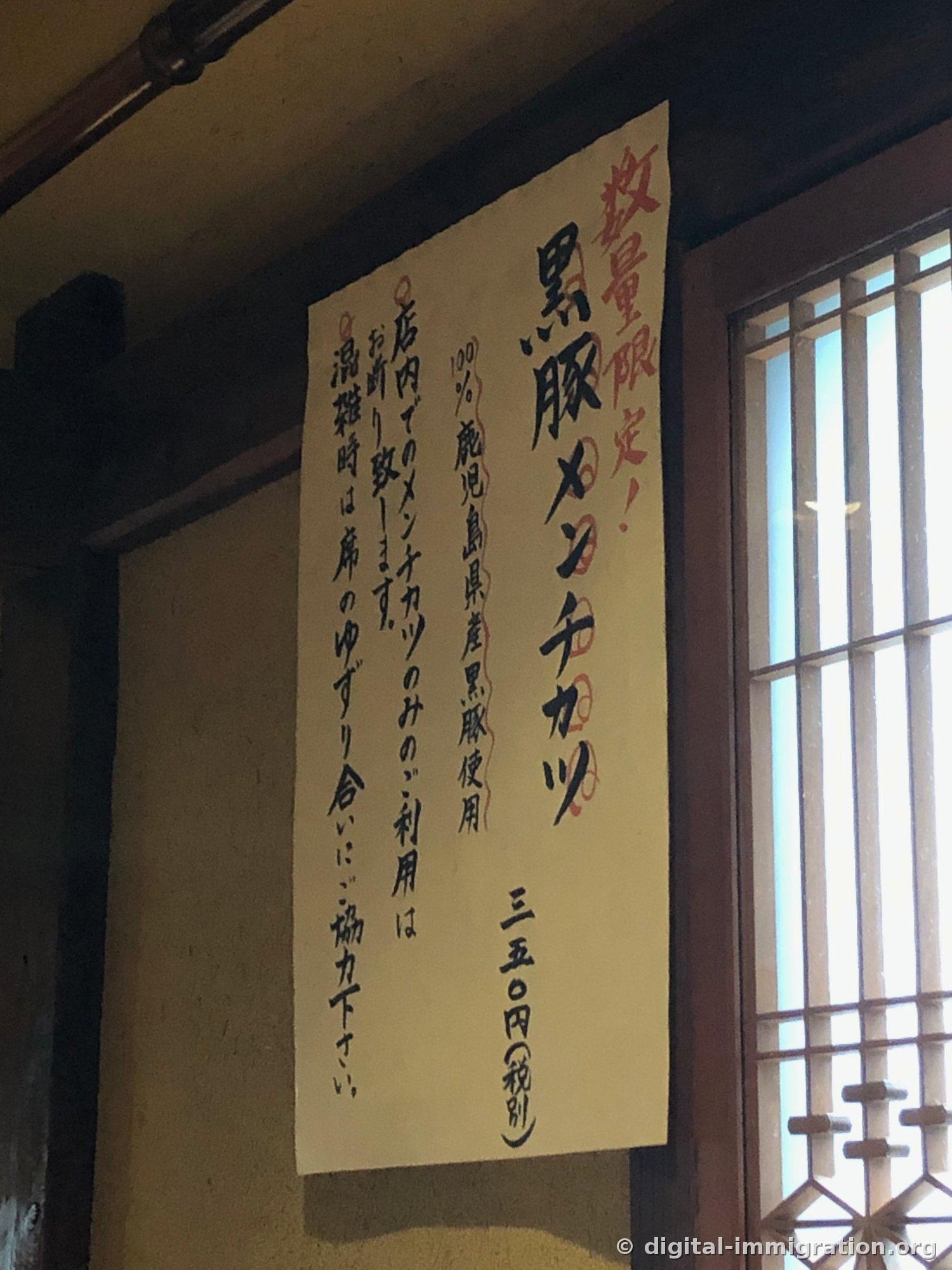 壁に貼ってある手書きの案内文。数量限定黒豚メンチカツ、鹿児島県産黒豚100パーセント使用、350円税別と書かれている