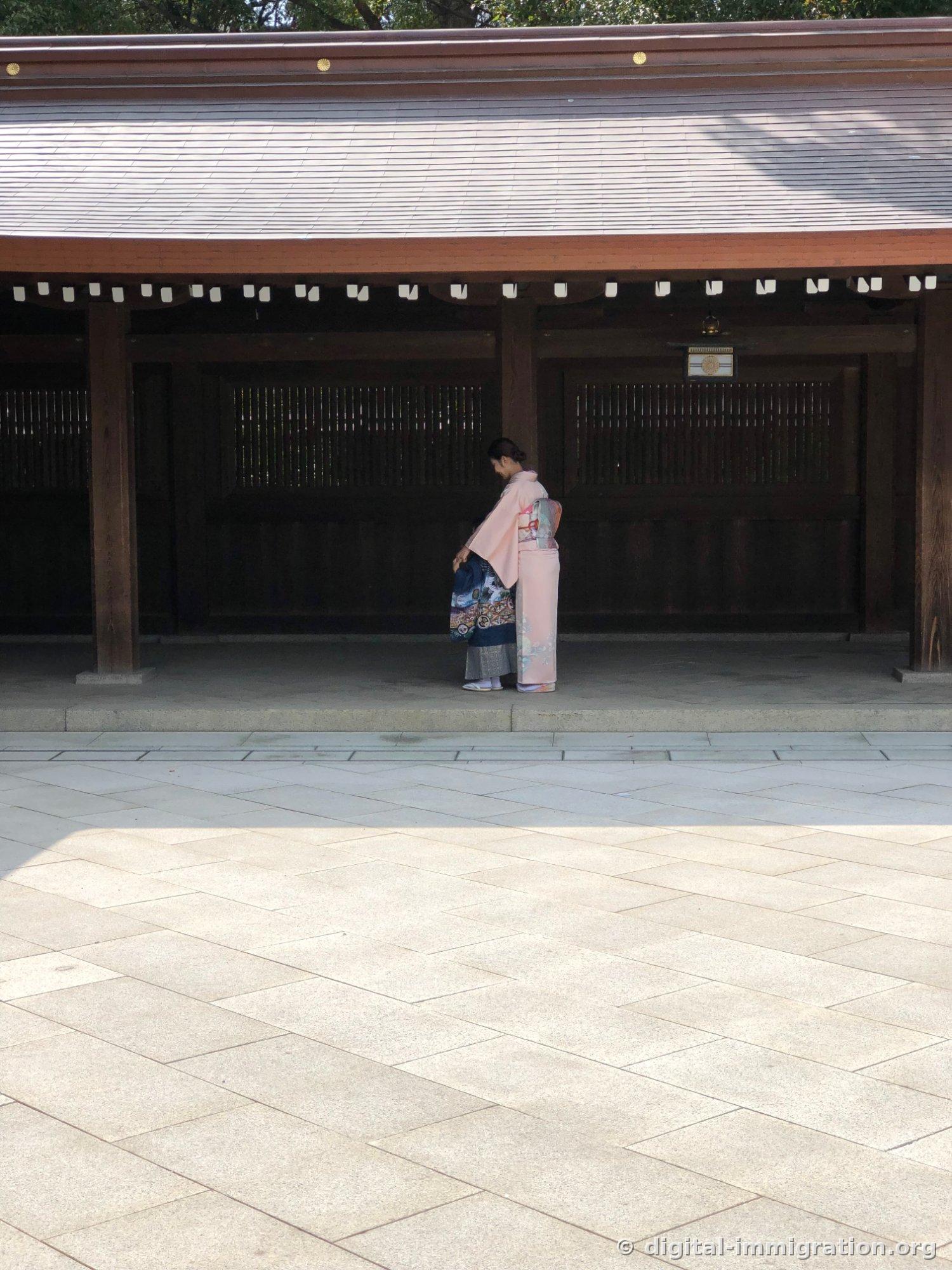 회랑 앞에서 분홍 기모노를 입은 여성이 남색 하오리 차림 아이의 옷매무새를 만져주는 모습