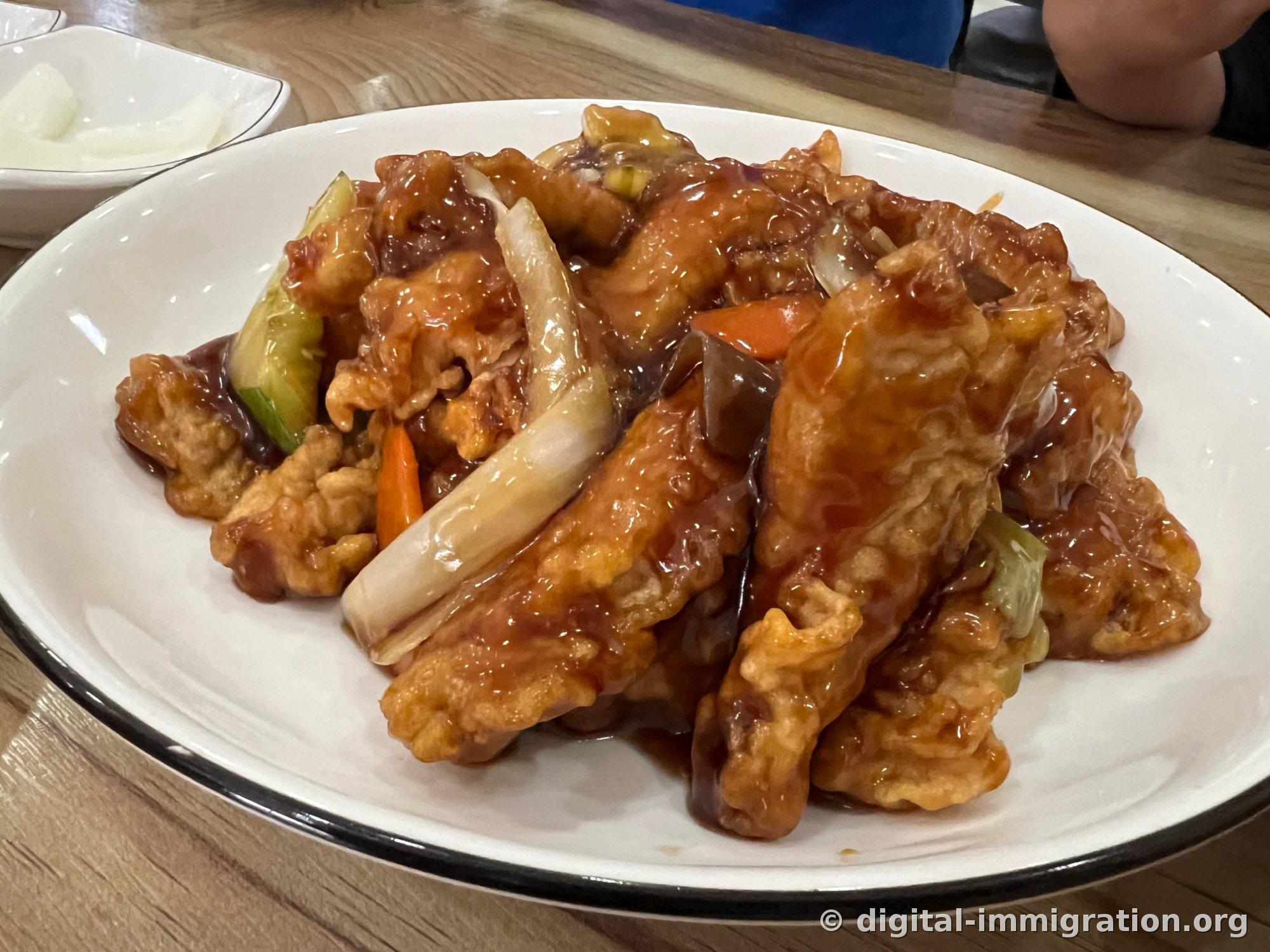Sweet and sour pork served with sauce poured on top. Cucumber, carrot, and wood ear mushroom are included.