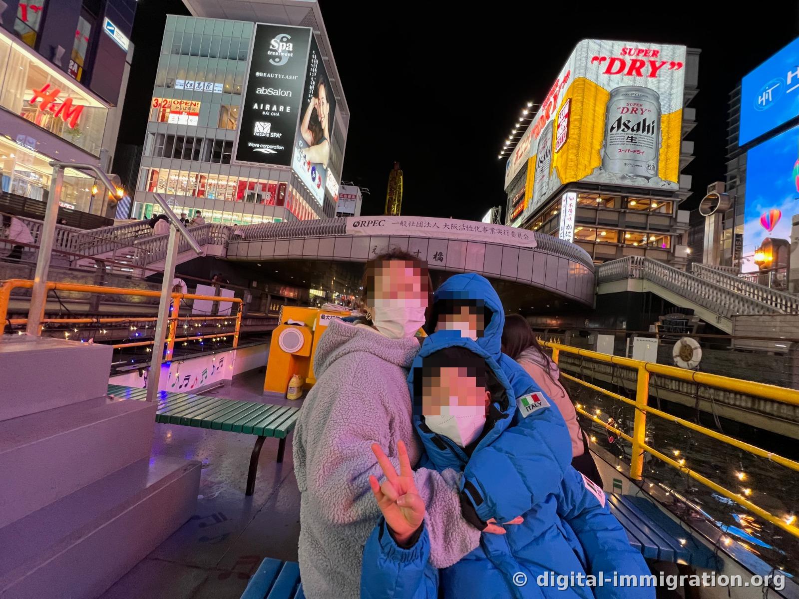 Une famille assis sur le siège de la croisière prenant une photo avec le pont Ebisu et l'enseigne Asahi Super Dry en arrière-plan