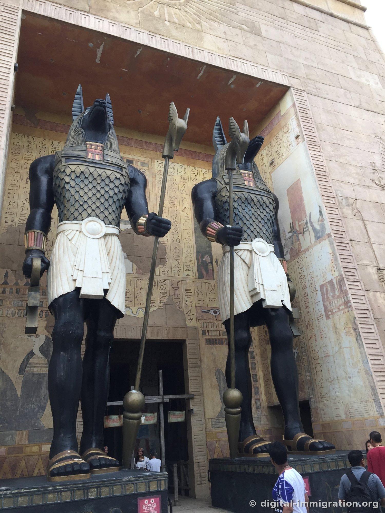 Two black jackal-headed Anubis statues at the entrance of the Egypt zone and temple walls covered with hieroglyphics