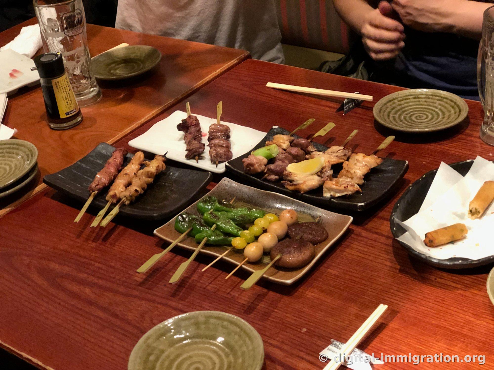 同样的餐桌布景从略微远处拍摄，右侧纸张上放着炸春卷和半杯剩余啤酒