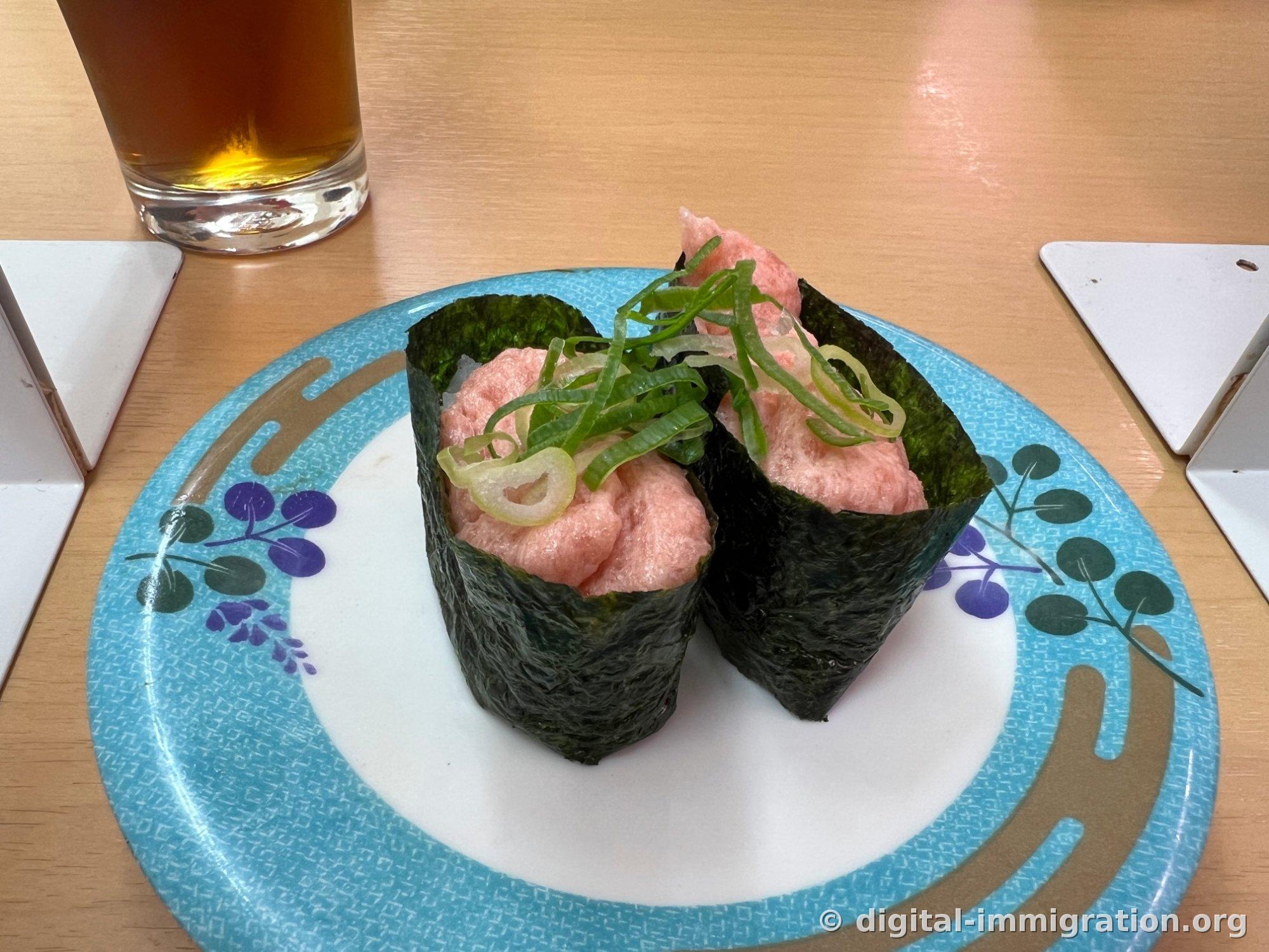 两个装满碎金枪鱼的海苔军舰卷上铺着切好的葱段