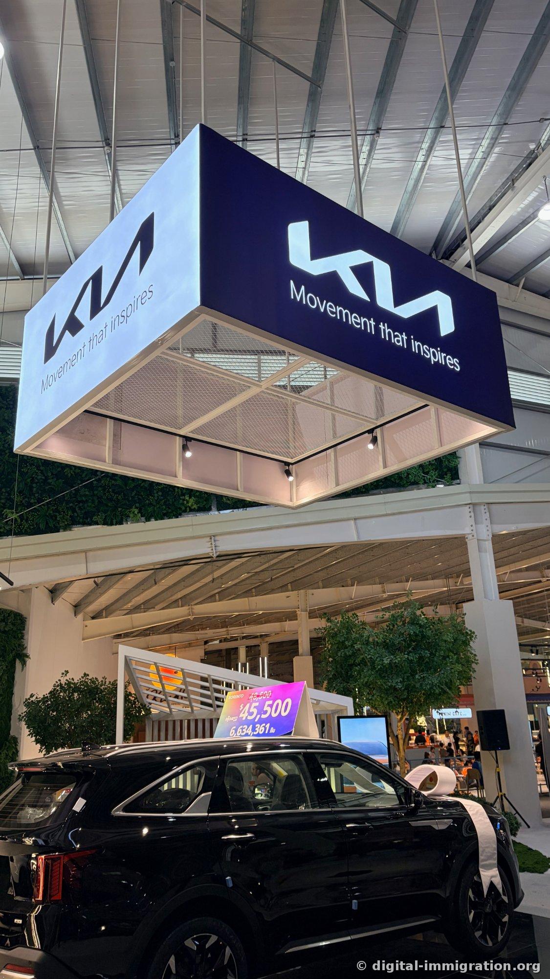 Kia 'Movement that inspires' sign hanging from ceiling above black Sorento, price tag showing $45,500 / 6,634,361 kip