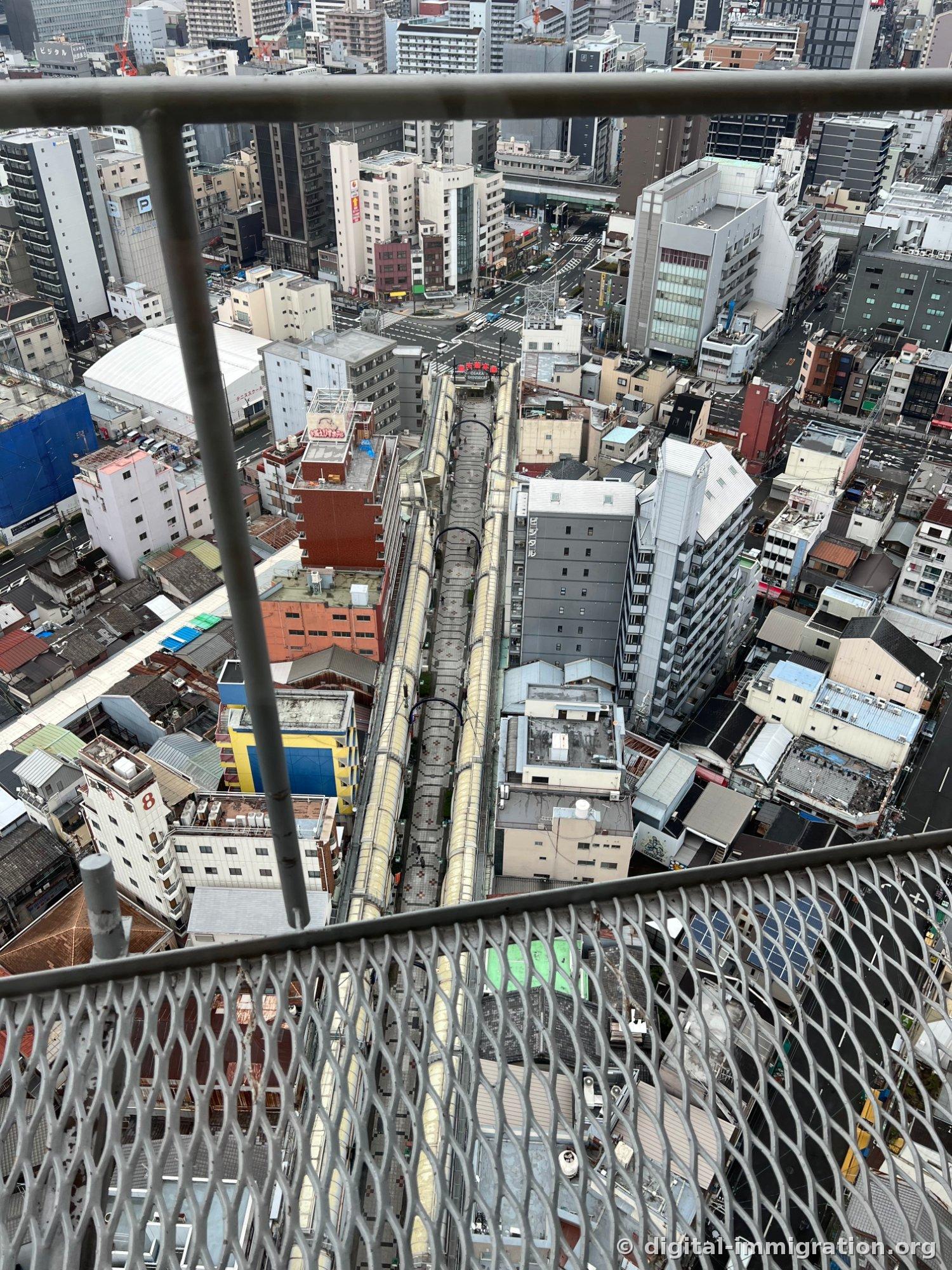 Looking straight down from the observation deck mesh railing at the Shinsekai arcade roofs and alleys