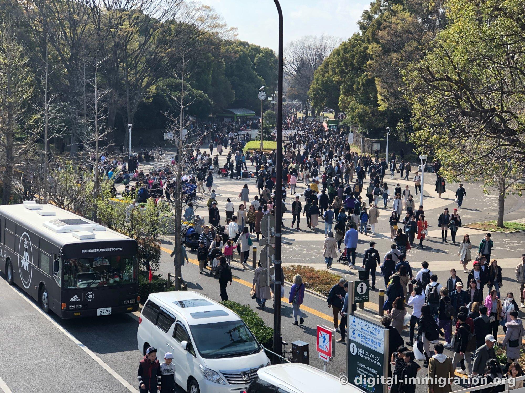 육교에서 본 요요기공원 앞 원형 무늬 광장을 가득 메운 인파와 정차한 검은 아디다스 러너스 도쿄 버스