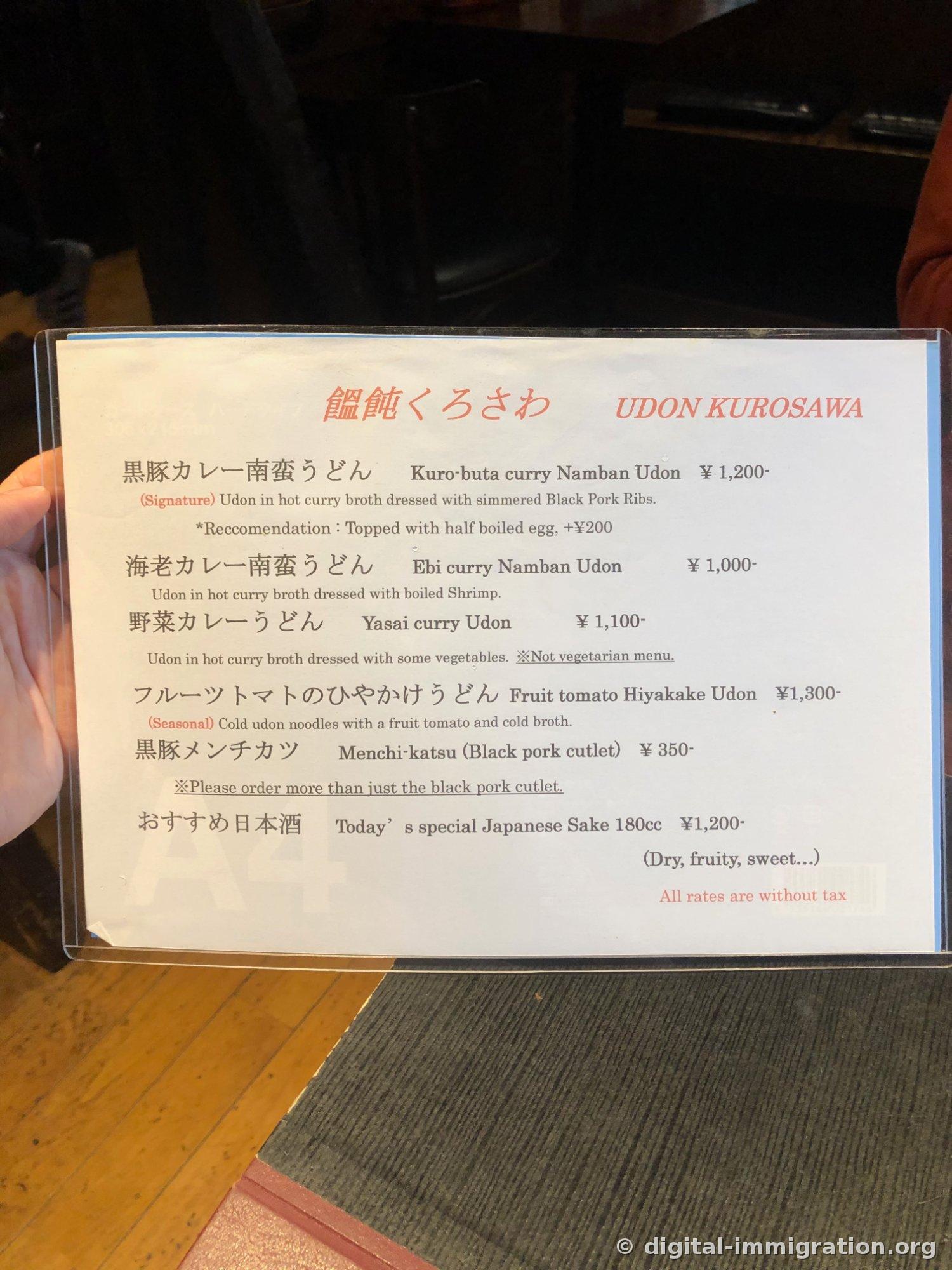 UDON KUROSAWAと書かれた日英併記のメニュー板。黒豚カレー南蛮うどん1200円、えびカレー南蛮うどん1000円、黒豚メンチカツ350円などが書かれている