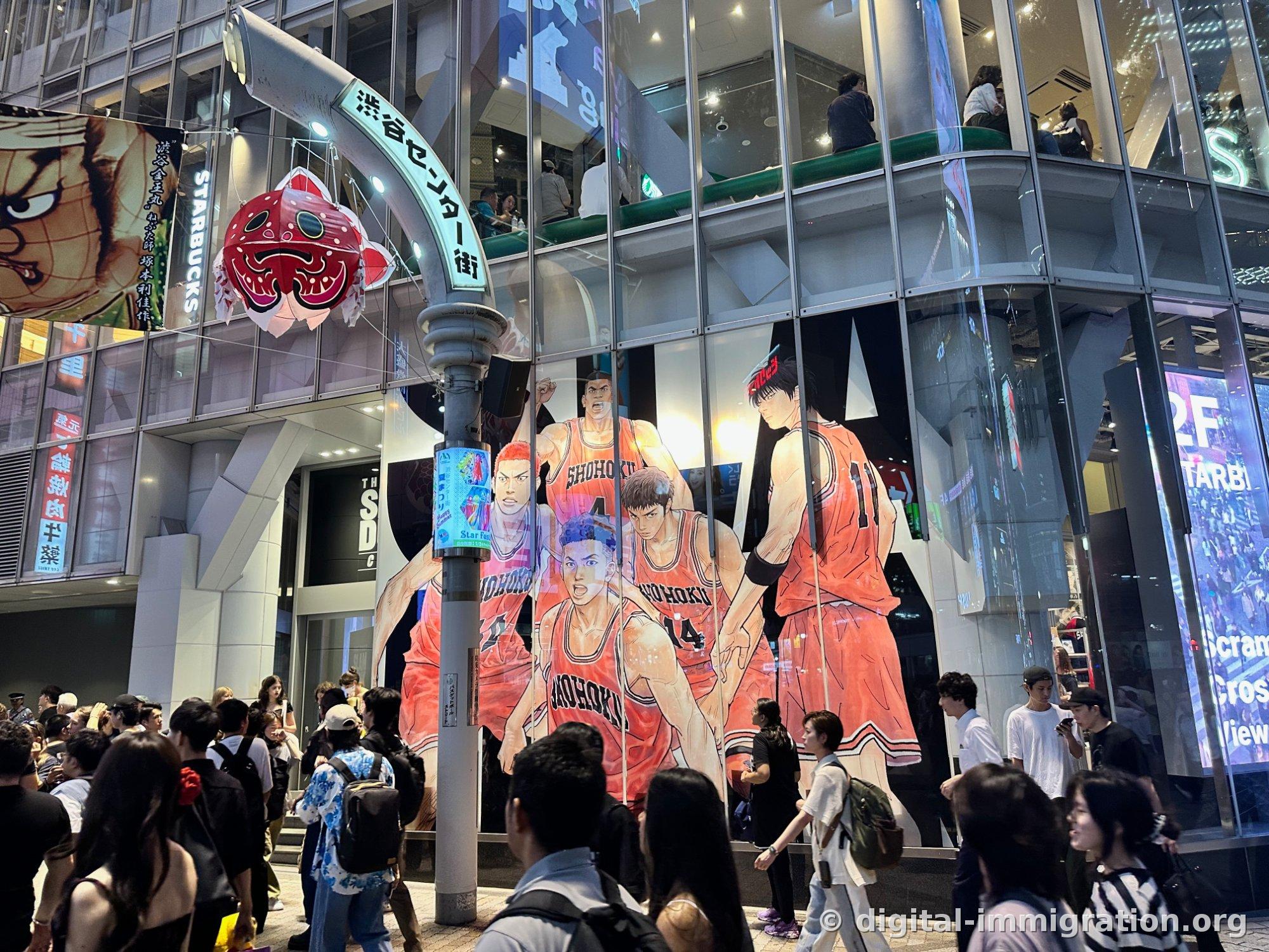 夜の渋谷センター街入口のアーチと赤い鯛の形の七夕飾り、建物の壁を覆う大型スラムダンクのイラスト
