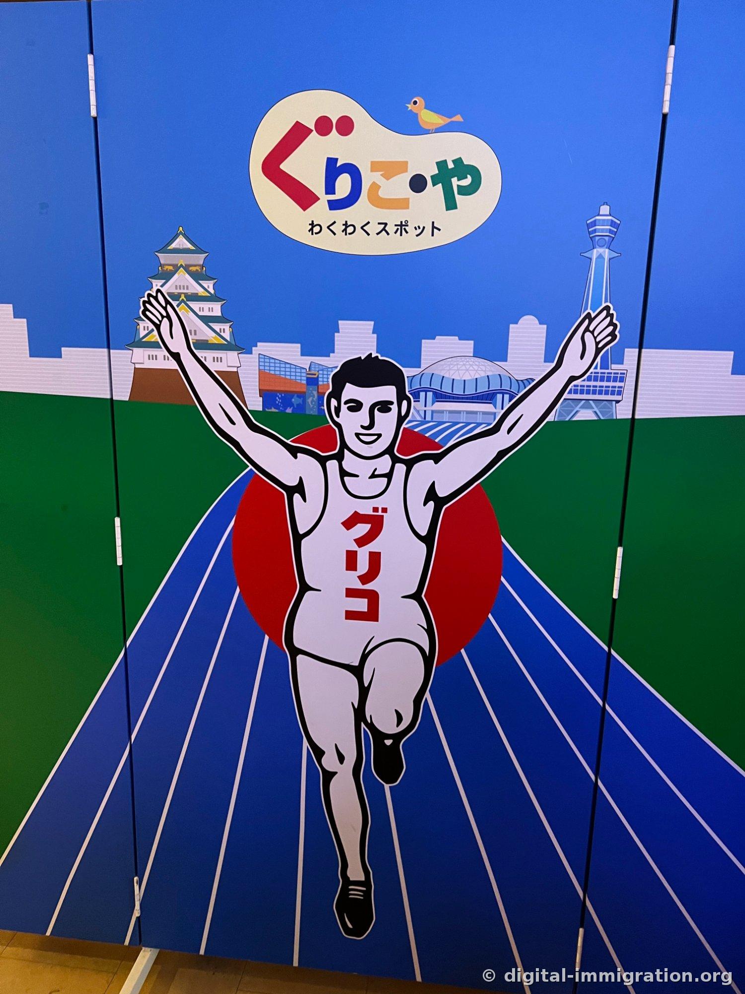 A Glico runner illustration running in front of a background with Osaka Castle and Tsutenkaku, with the 'Glico Wakuwaku Spot' logo