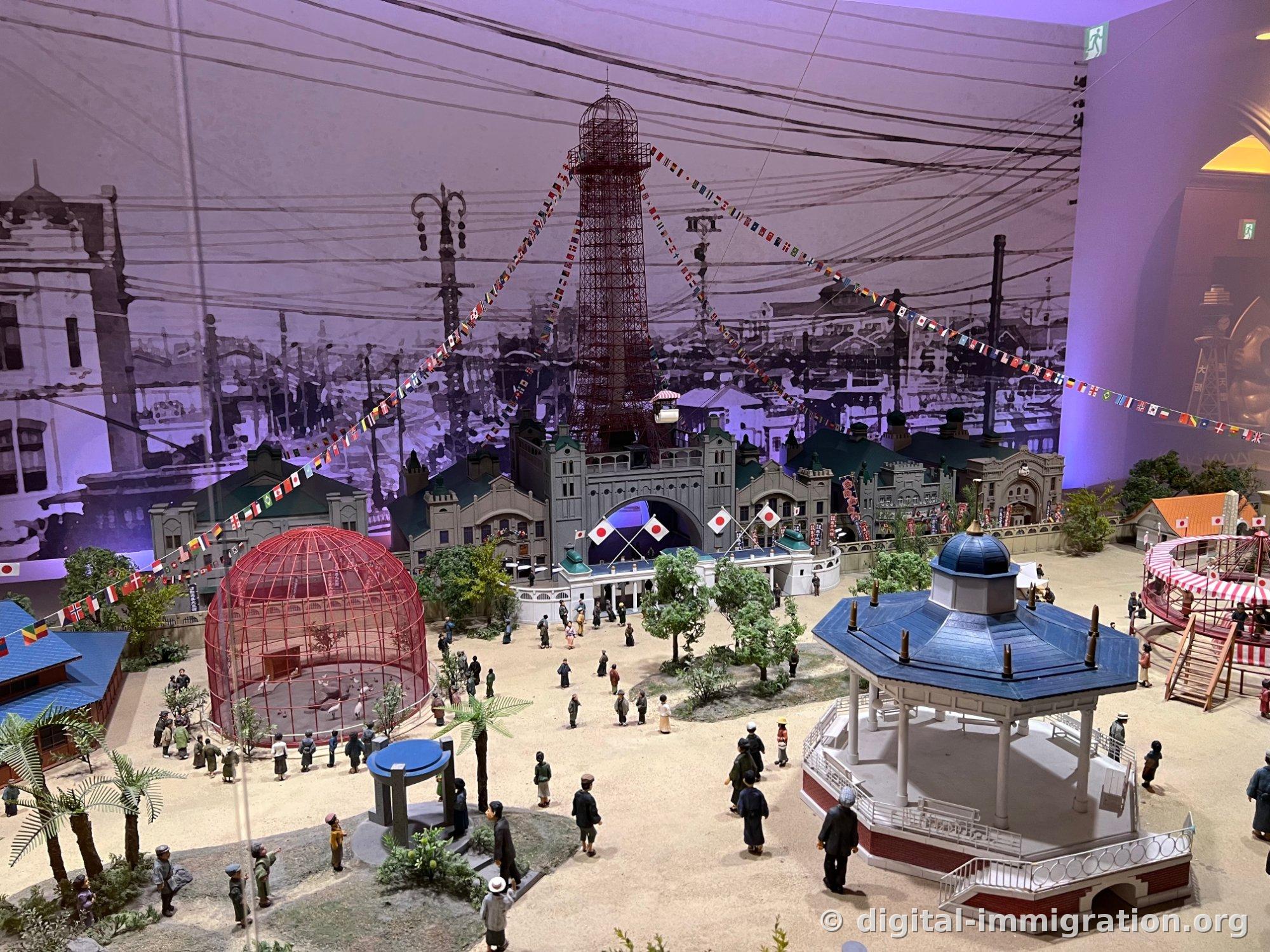 A diorama recreating the original Tsutenkaku and Luna Park, with international flags and red birdcage and figures arranged