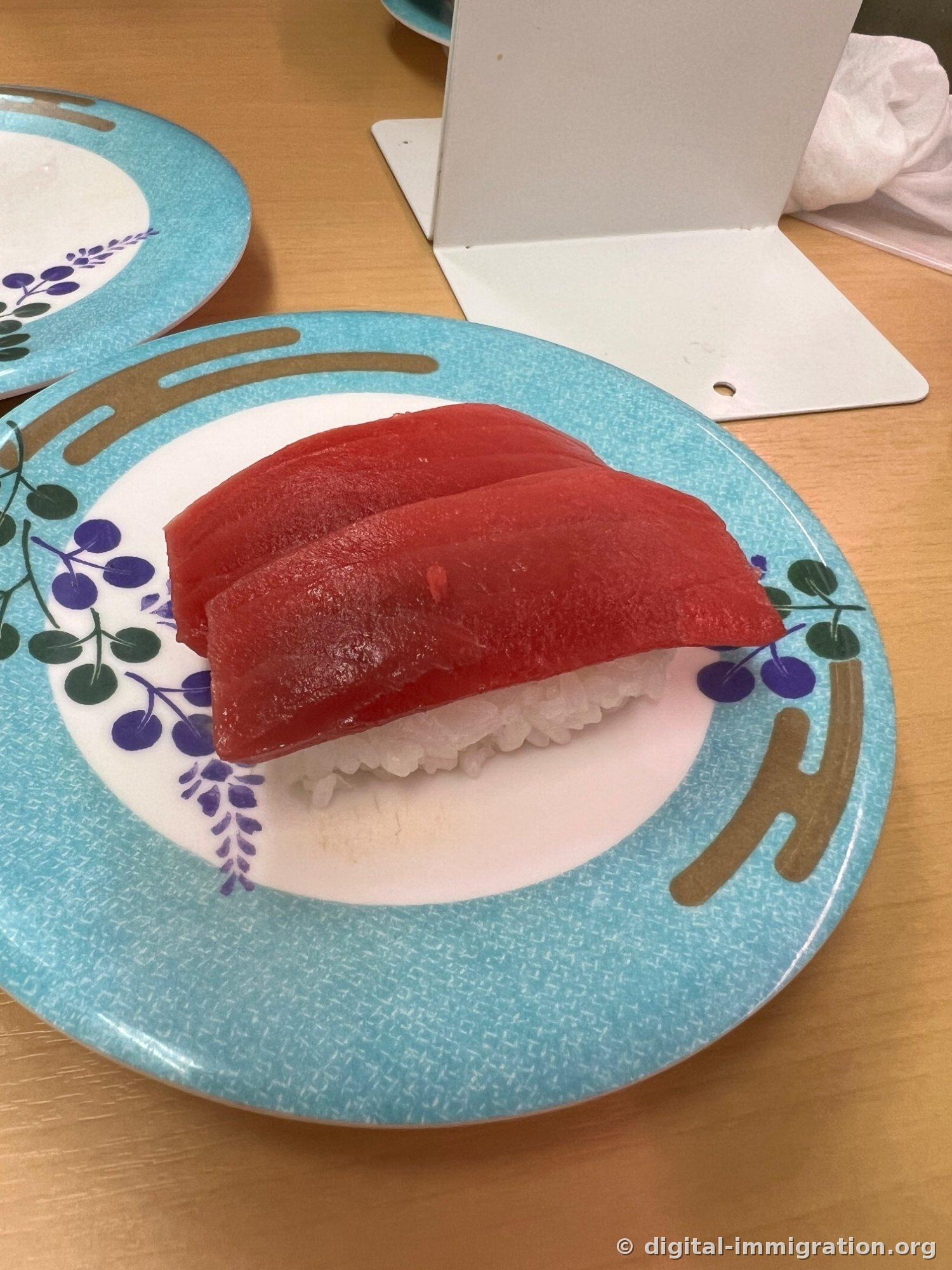 浅蓝色边框配紫色果实纹样的盘子上放着两个金枪鱼赤身寿司