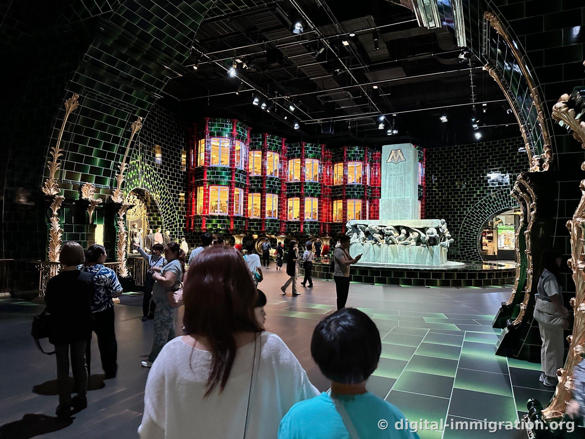 A massive green-tiled hall with red columns and lit windows at the center, and a large stone statue inscribed with MAGIC IS MIGHT