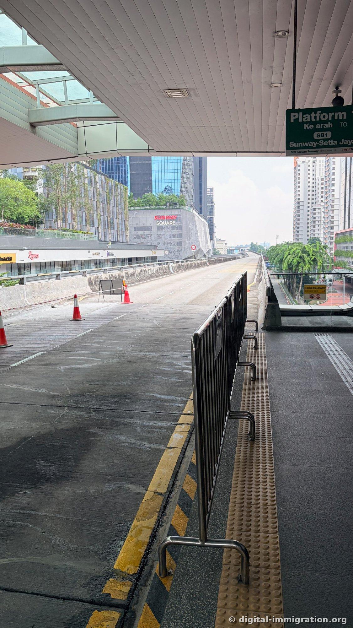 公交车驶离后空荡荡的高架 BRT 专用道路和远处可见的 SUNWAY SQUARE 建筑、工程护栏筒