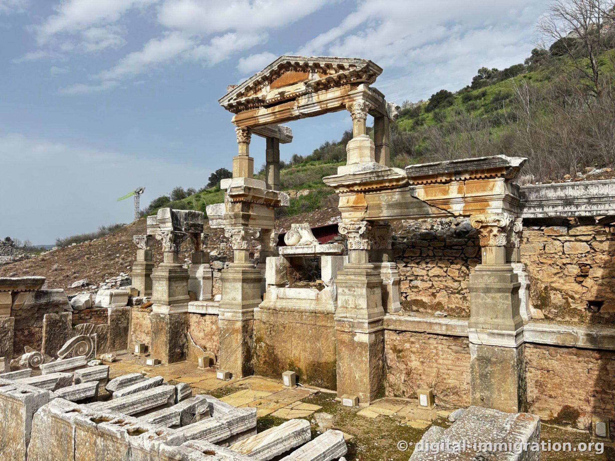 Trajan Fountain with two Corinthian columns supporting a triangular pediment, stone pieces lying in the courtyard