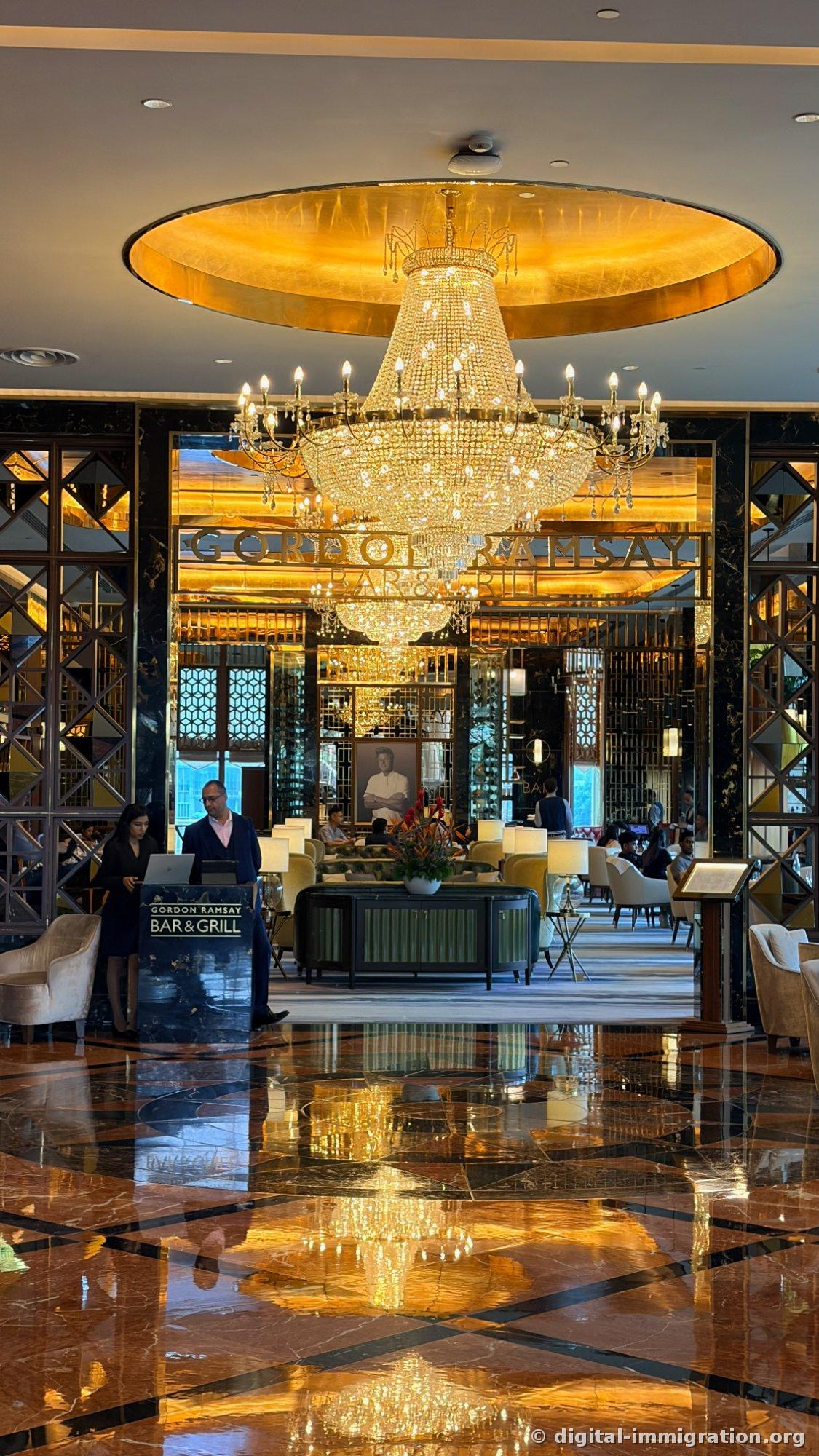 金箔天花板和大型水晶吊灯的 Gordon Ramsay Bar & Grill 入口和大理石地板上的倒影