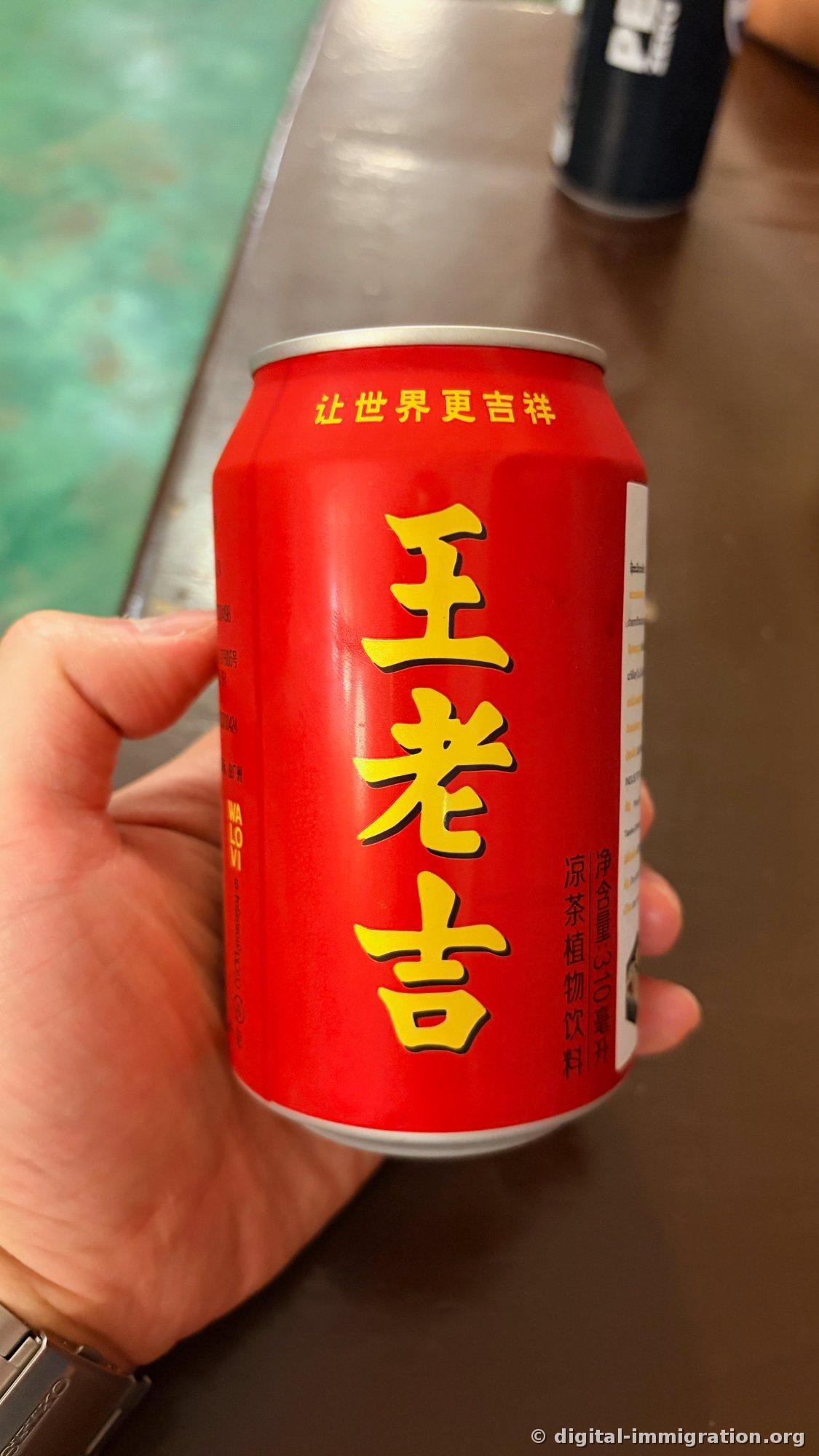 手に持つ赤色の王老吉缶。黄色い漢字と『凉茶植物饮料 310毫升』の表記が見える