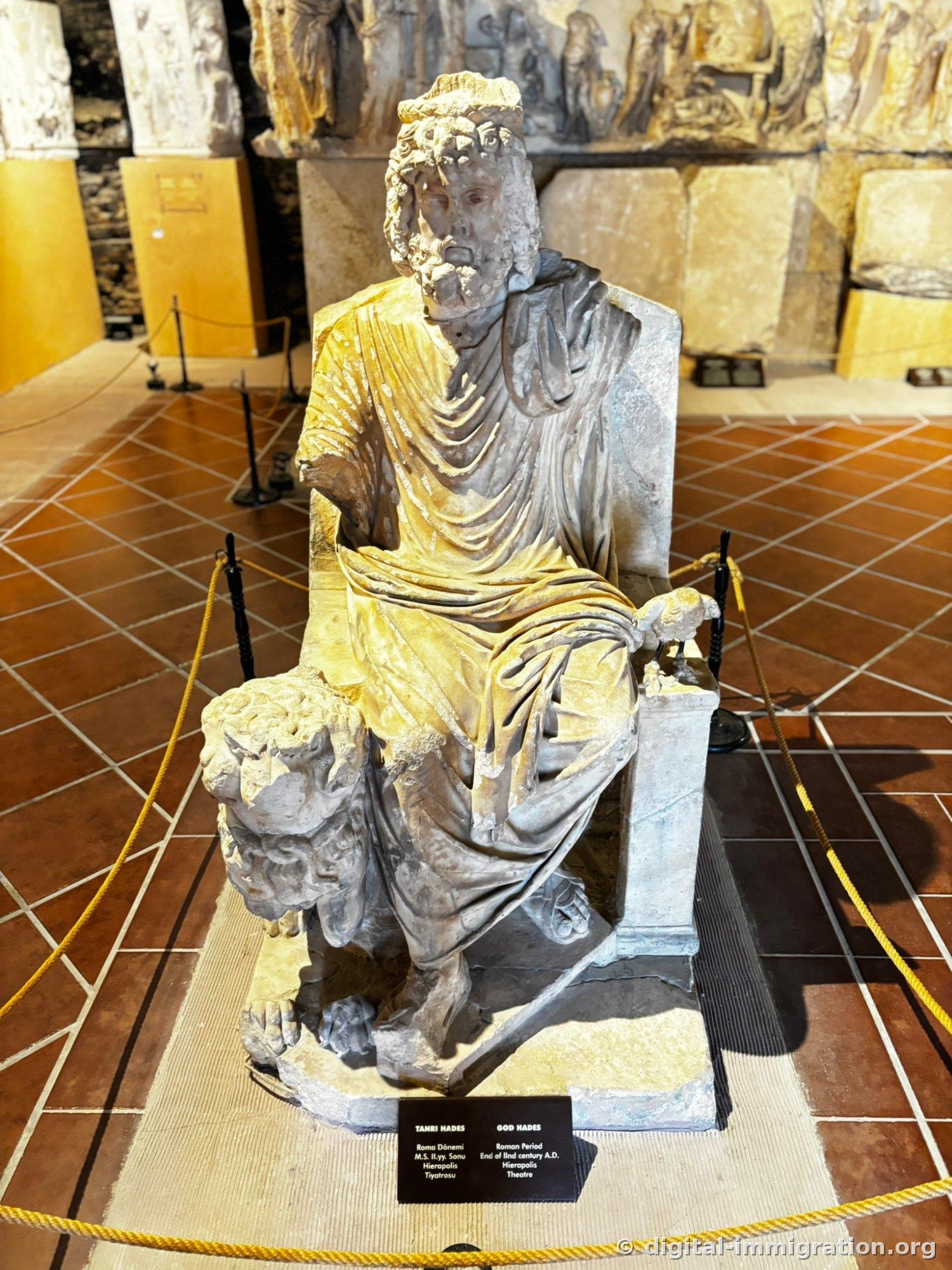 Bearded Hades statue seated on a throne, with a form resembling Cerberus with a broken head at his feet to the left, a small bird sculpture perched on the right pedestal