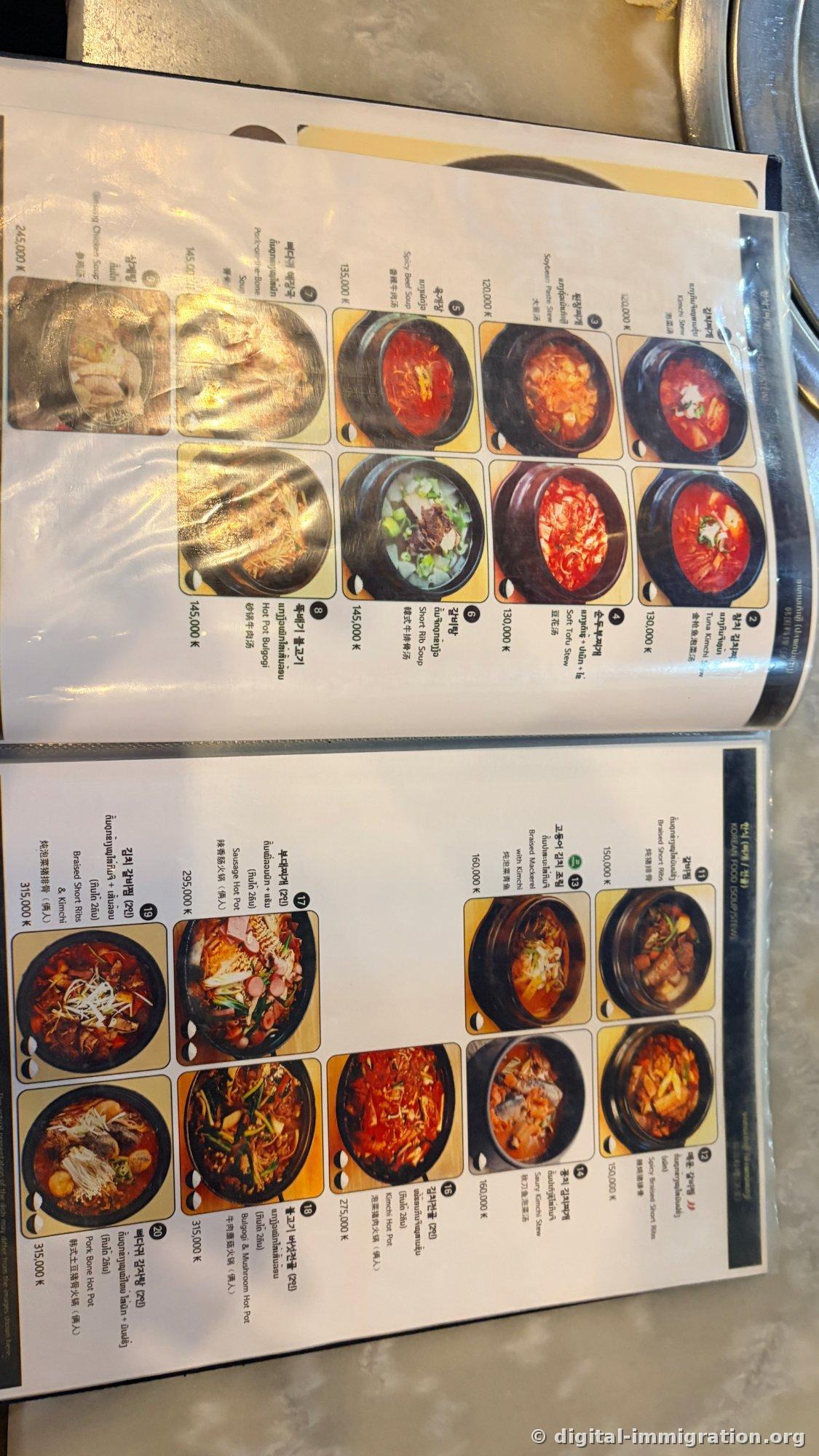 Double page du menu de HANCOOK rédigée en coréen, laotien, anglais et chinois. On y voit des photos de soupes et de jeonggol avec leurs prix en kip : kimchi-jjigae 120 000 kip, yukgaejang 135 000 kip, samgyetang 245 000 kip, galbi mijoté 315 000 kip, entre autres
