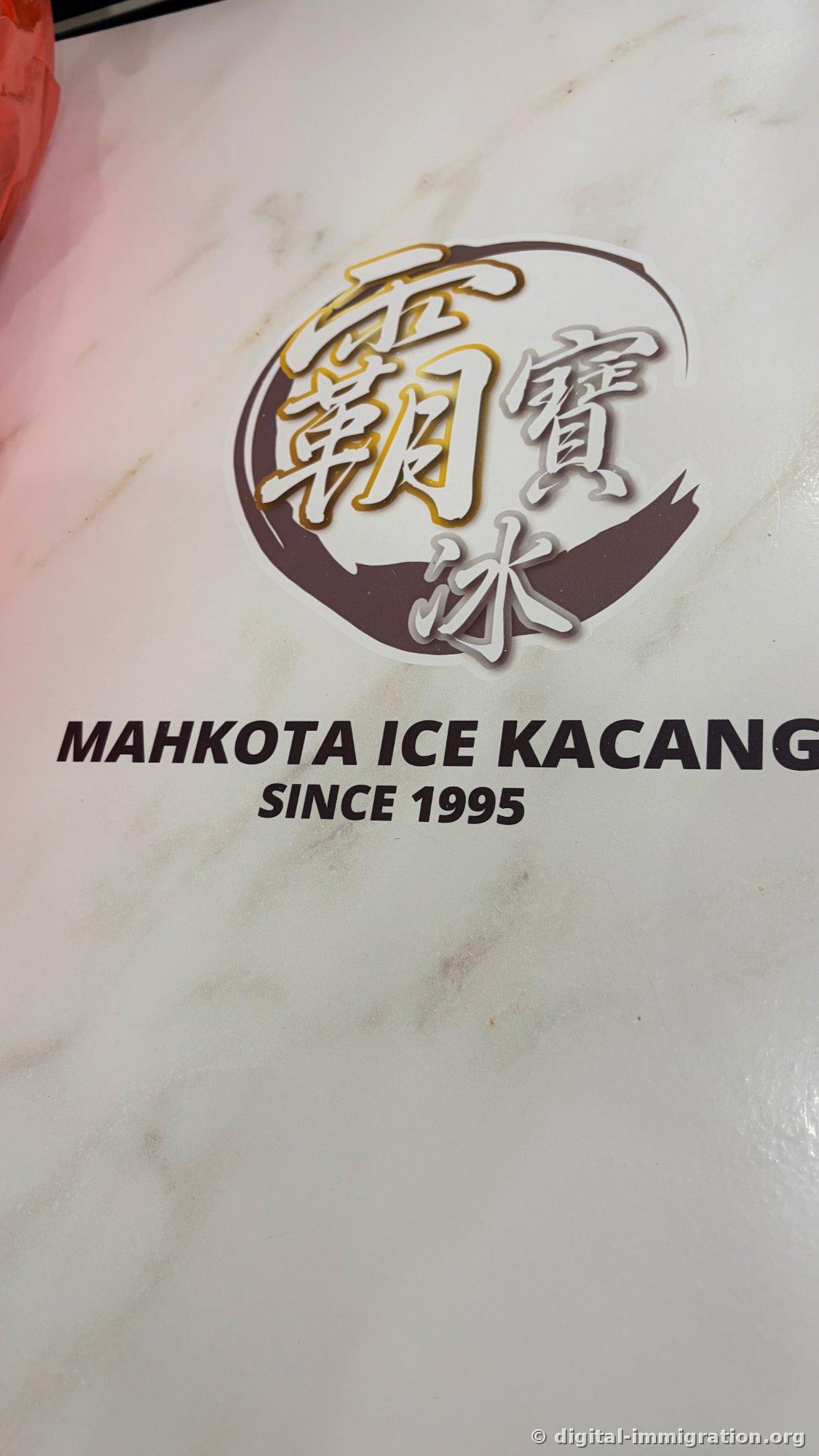 Logo sticker on a marble-patterned table. A Chinese character logo inside a brown circle with 'MAHKOTA ICE KACANG SINCE 1995' written below.