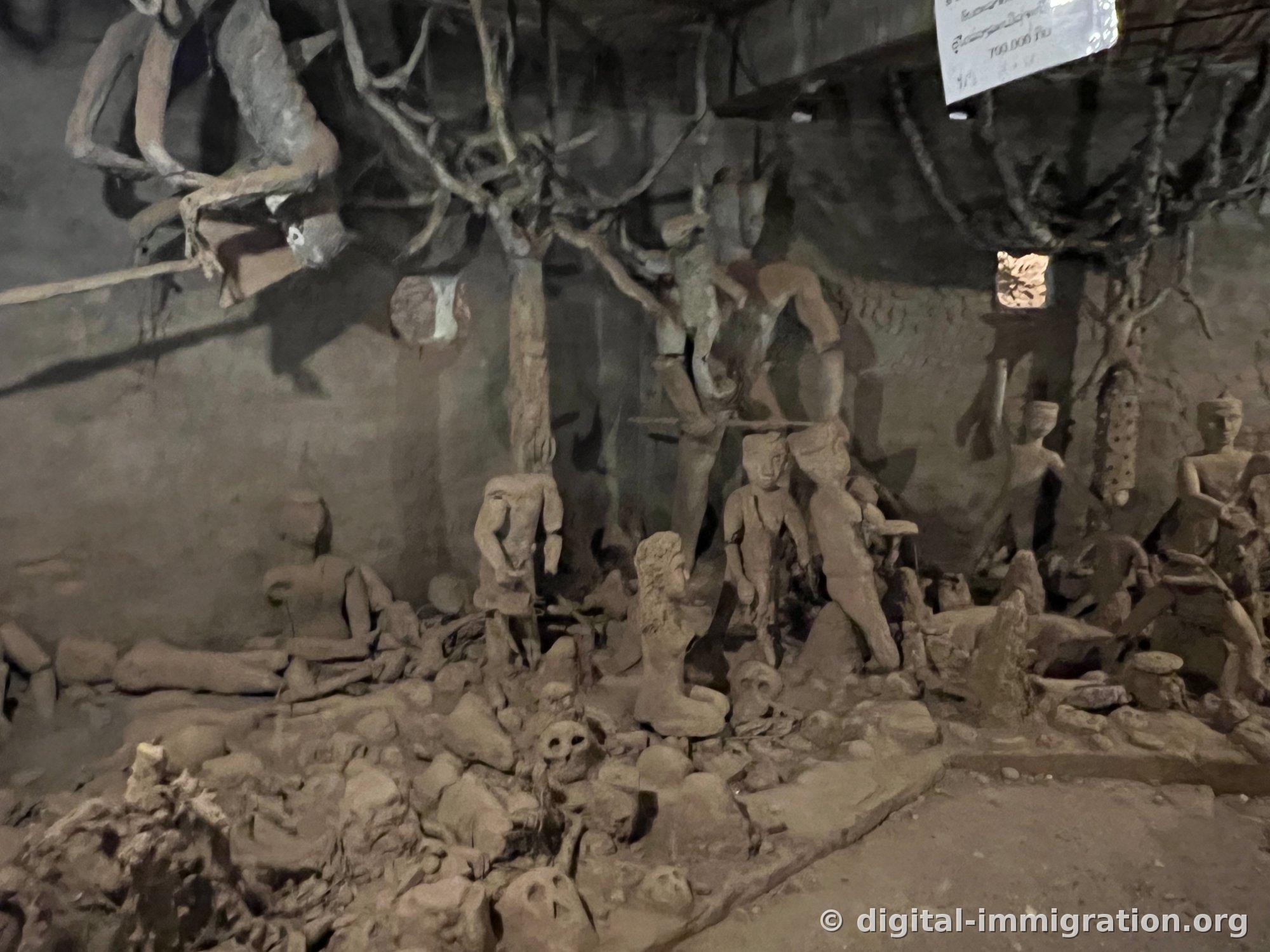L'intérieur sombre du premier étage du bâtiment citrouille, avec des formations d'arbres nus portant des figures humaines et des sculptures de crânes couvrant le sol