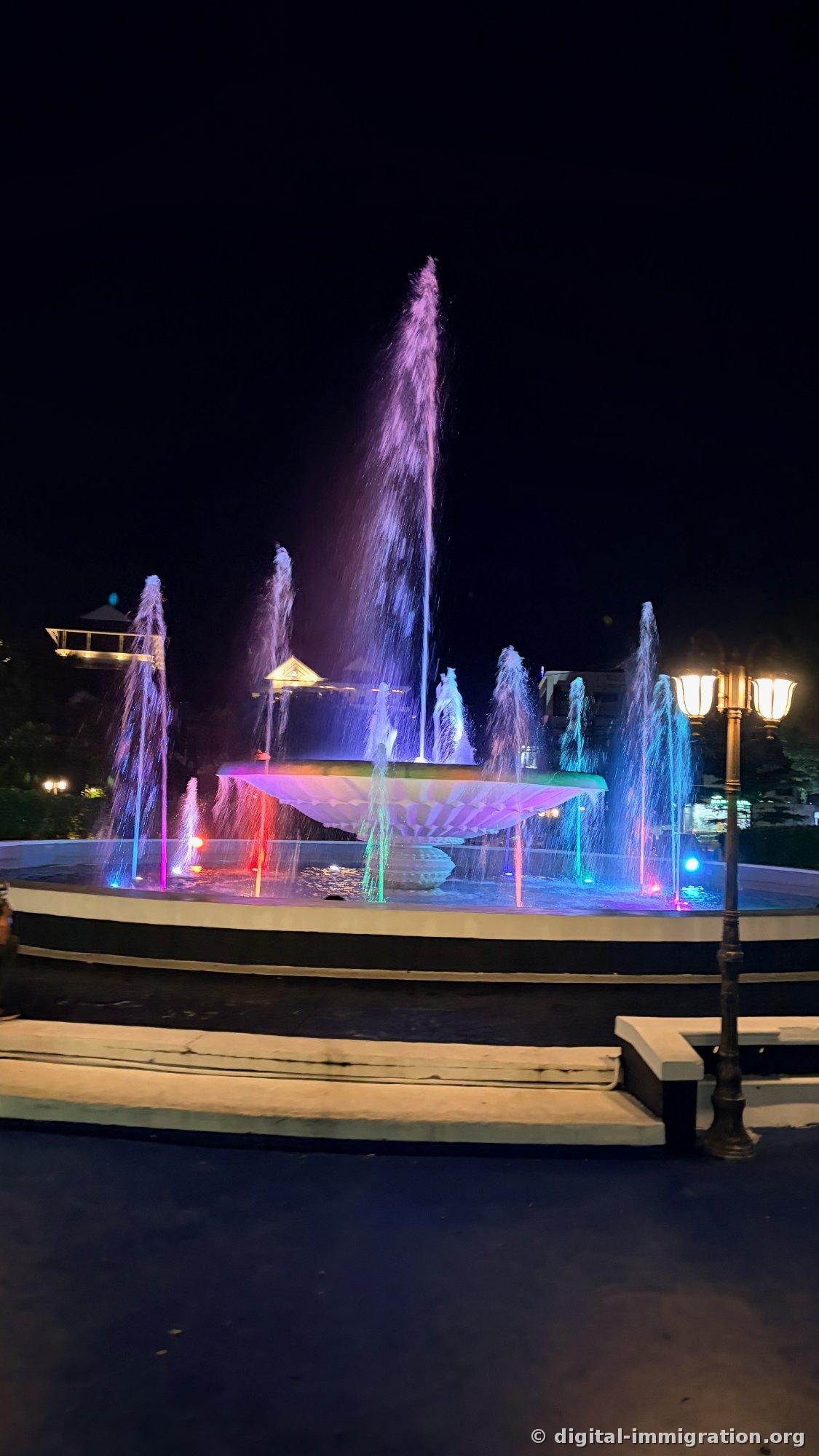 Nuit complètement sombre, le jet central de la fontaine Nam Phou s'élève haut et les jets périphériques brillent en rose, vert et bleu - gros plan