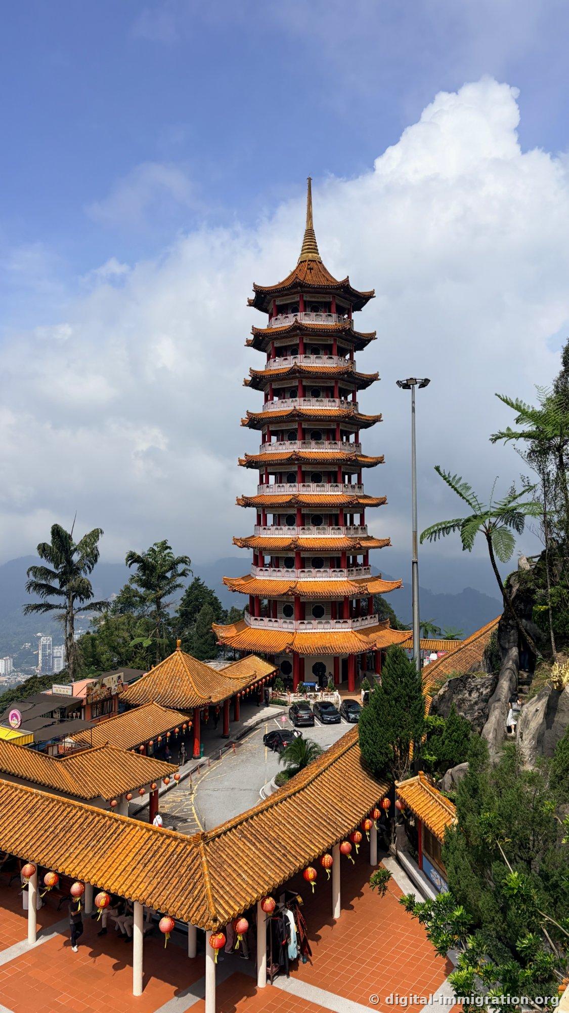 Vue de la pagode de 9 étages et de l'ensemble du temple pris d'en haut, avec les toits orange se chevauchant, et une crête montagneuse enveloppée de nuages en arrière-plan